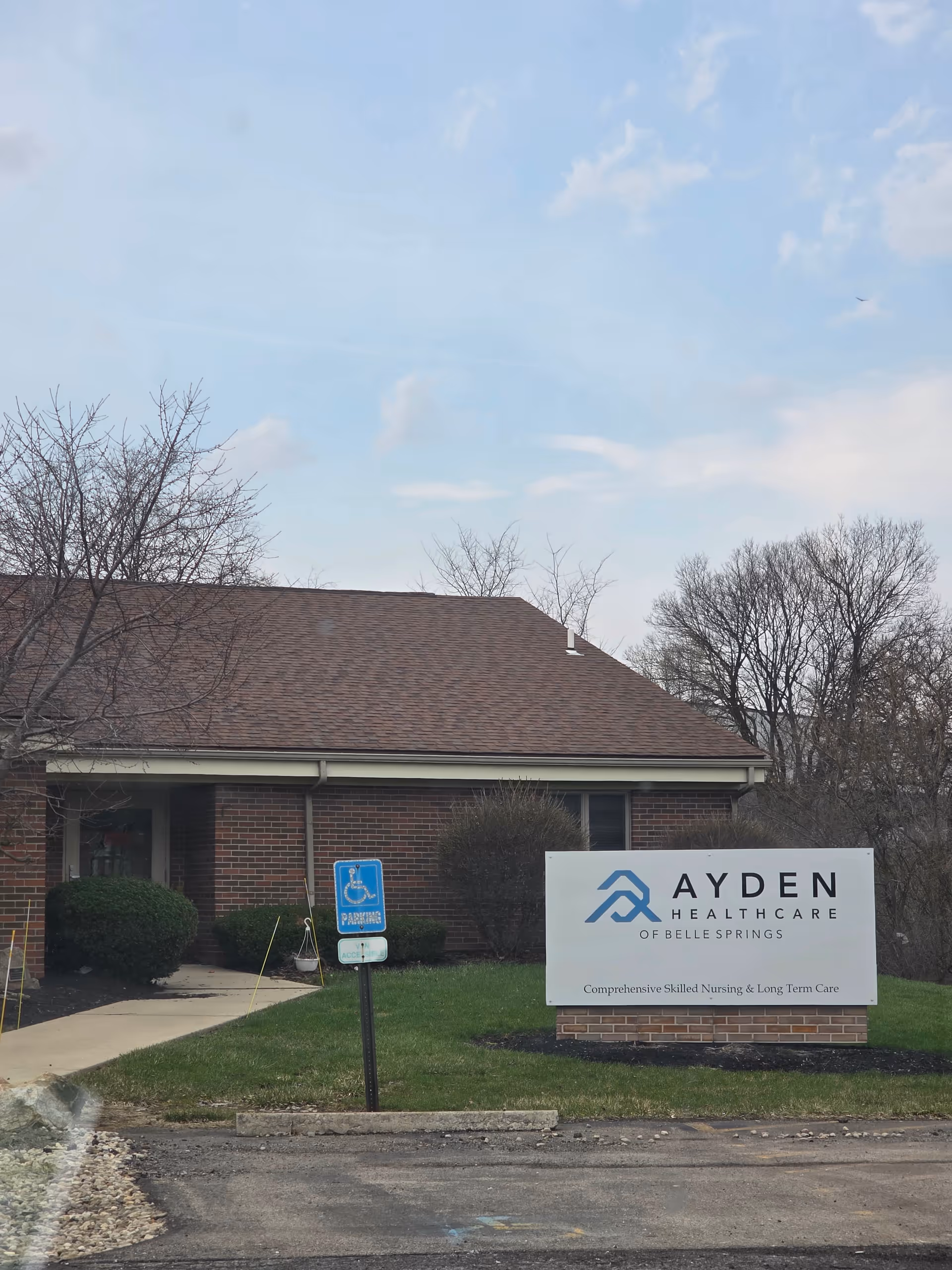 Brick healthcare facility exterior with a front entrance, handicap sign, and large sign.