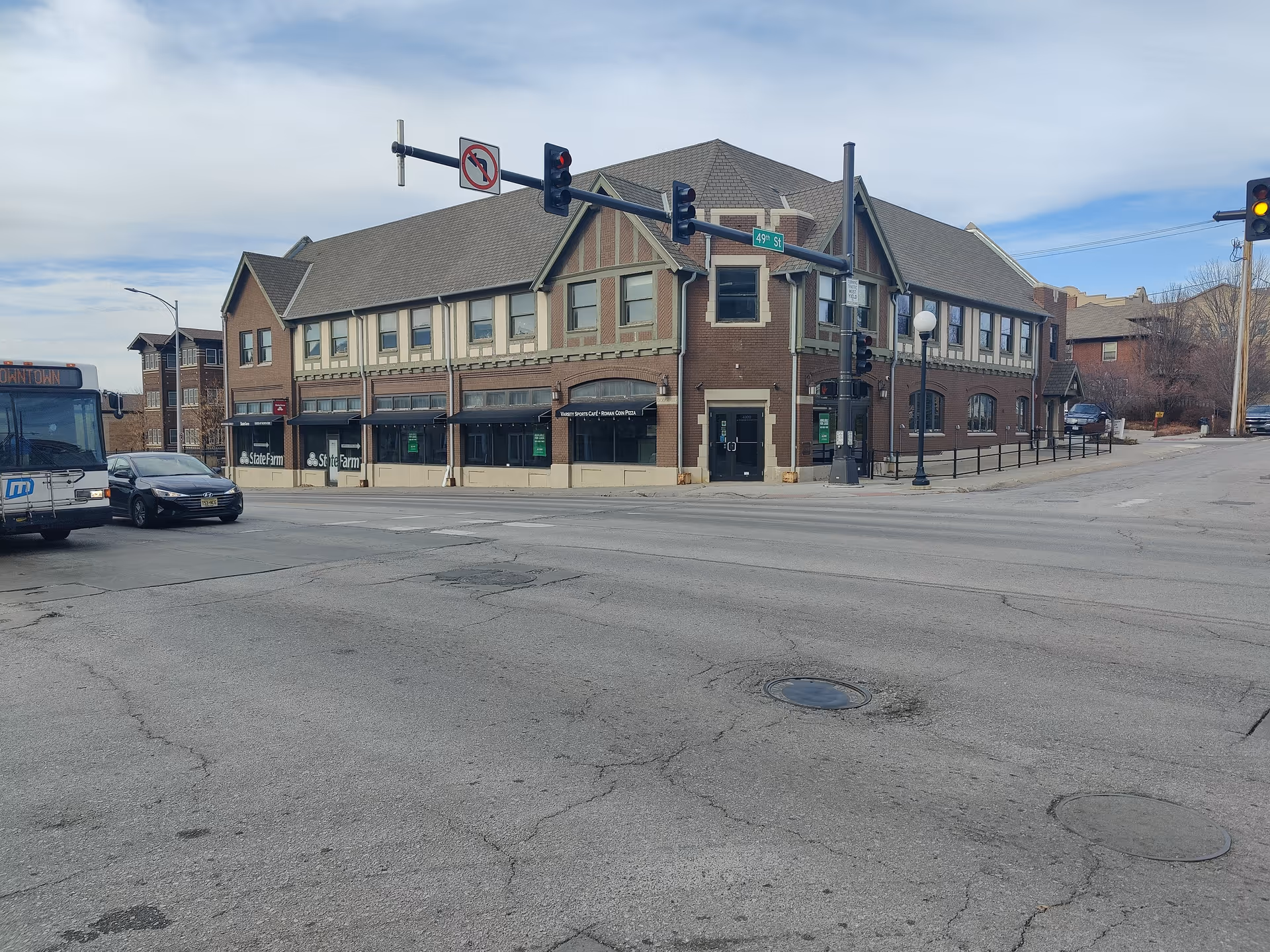 Corner street view of a brick building with storefronts and traffic lights.