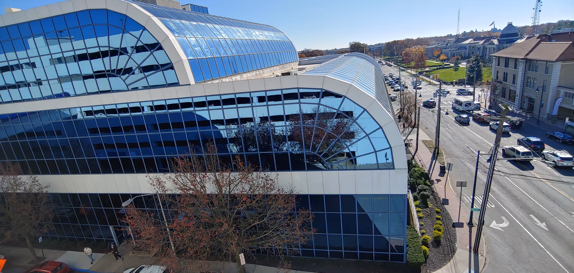 Aerial view of a modern glass front medical building along a tree lined street.