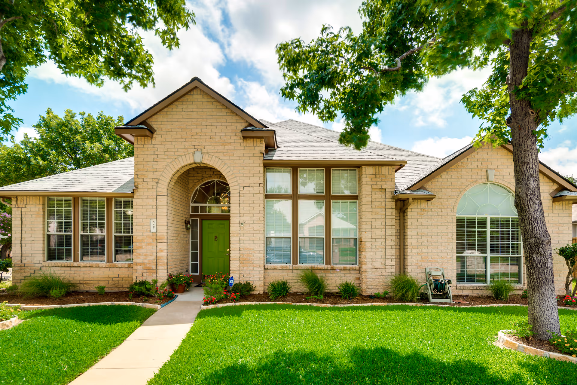 Brick senior living facility with green front door, large windows, and manicured lawn.