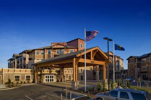 Exterior view of The Springs at Tanasbourne, a multi-story senior living facility with a covered entrance.