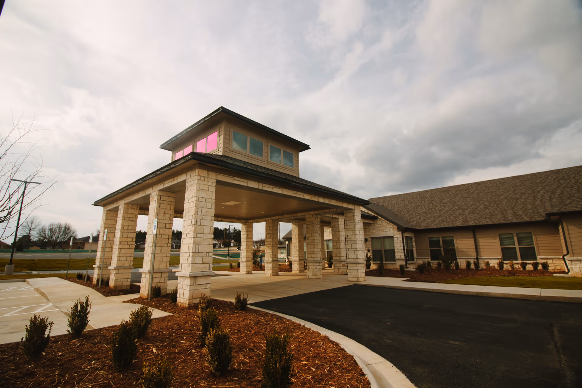 Front entrance with stone pillars and a covered drive-through at a senior care facility.