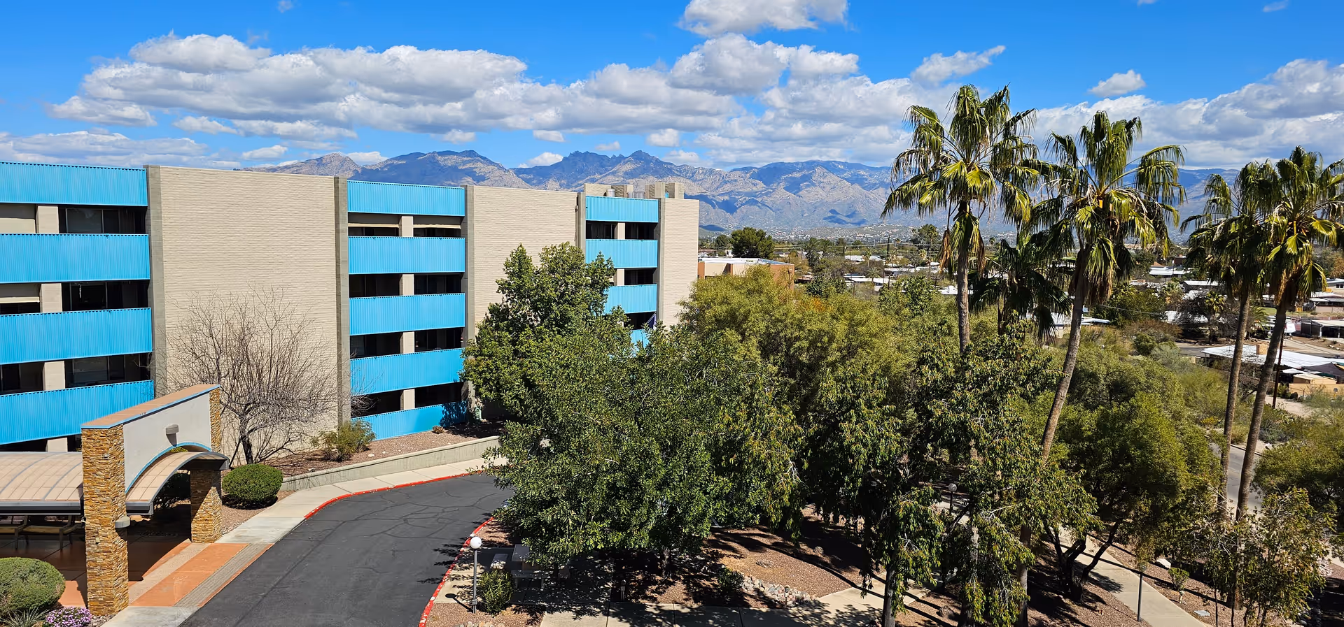 Exterior view of Cascades of Tucson featuring blue balconies and palm trees
