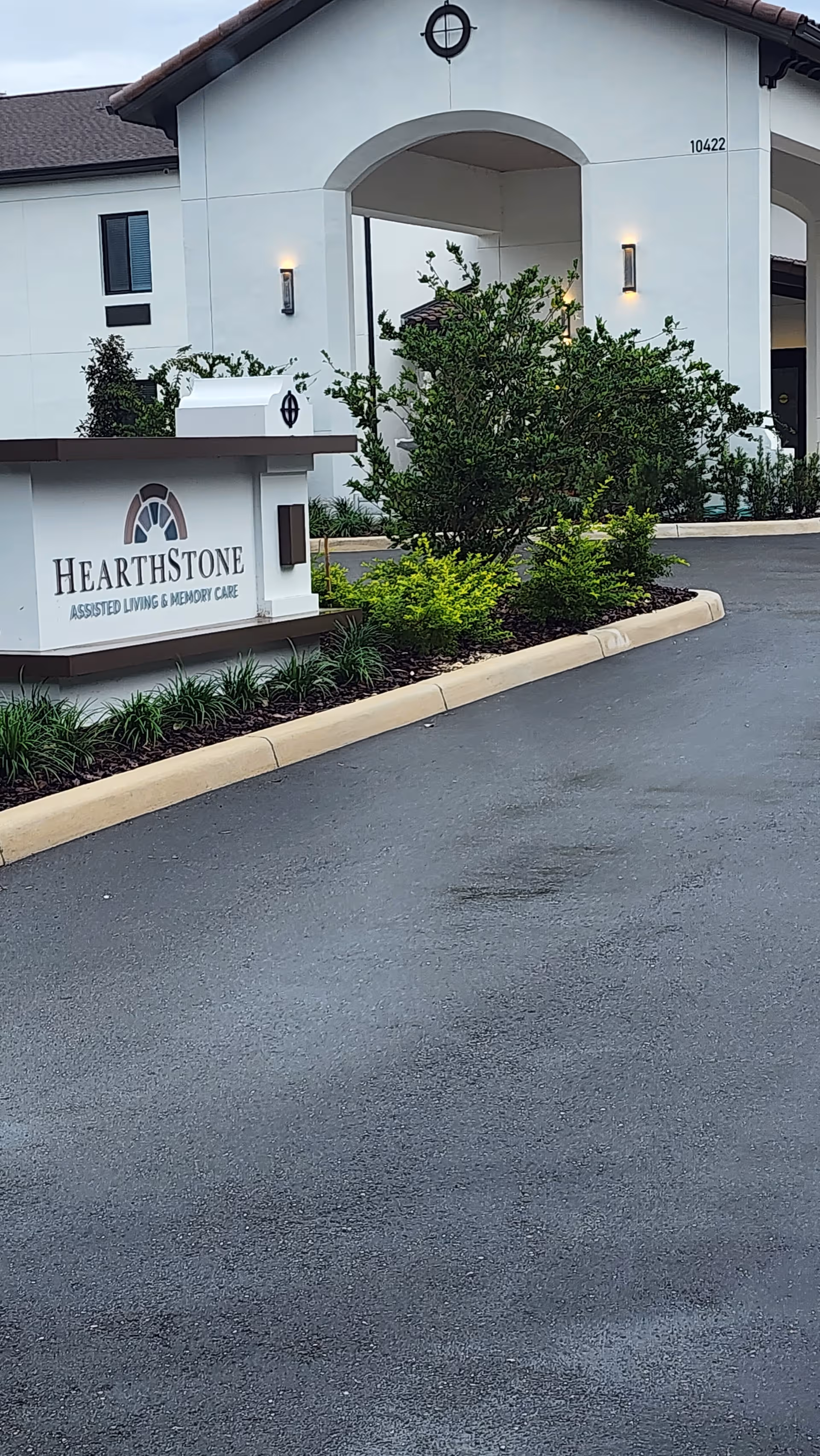 Front view of HearthStone at Wildwood entrance with sign and landscaped surroundings.