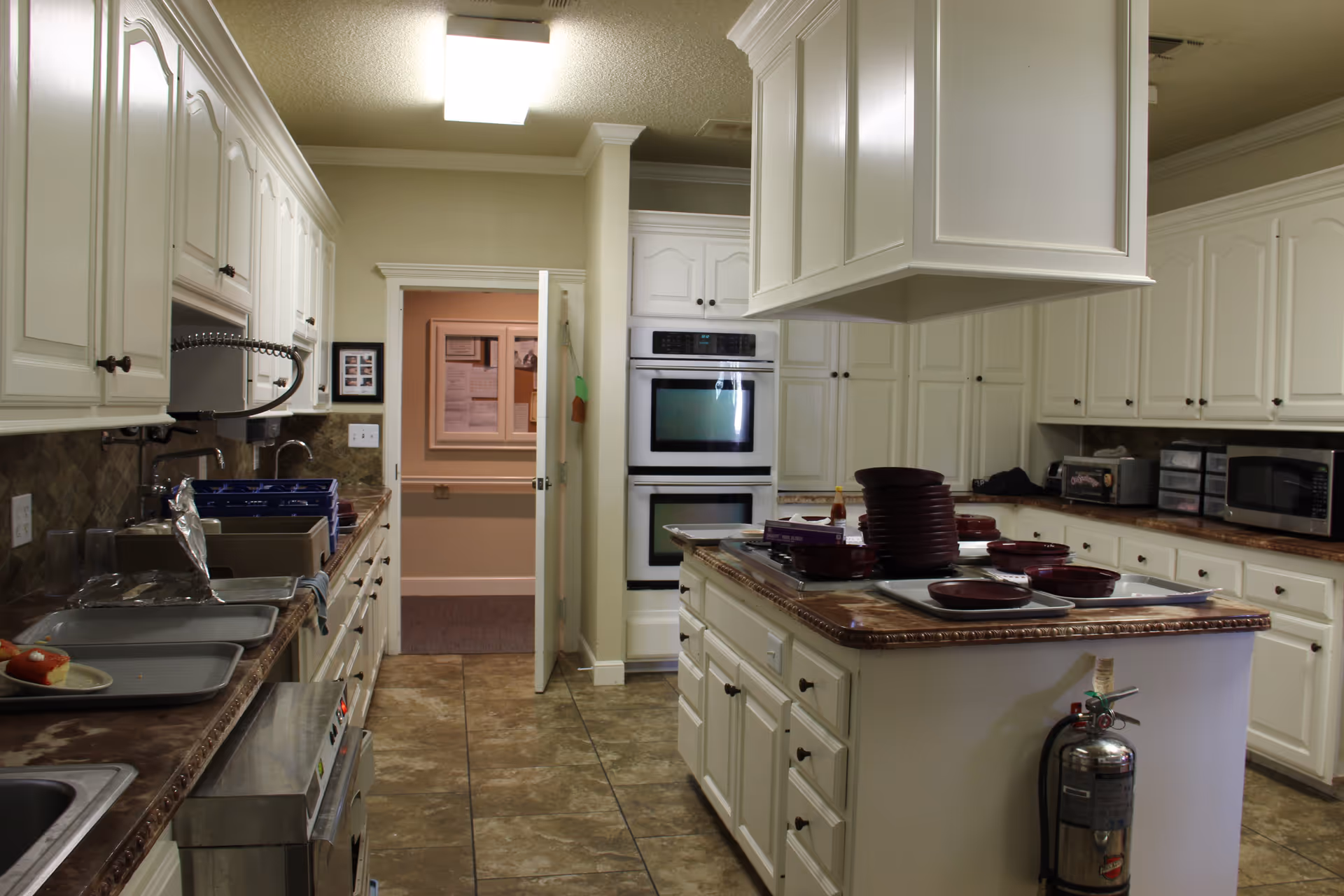 Bright white kitchen with island, gas stove, double oven, and tall cabinetry in Wilshire on 4th.