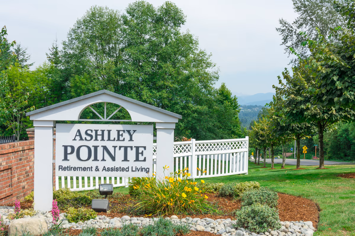 Ashley Pointe Retirement & Assisted Living sign with greenery and a white fence
