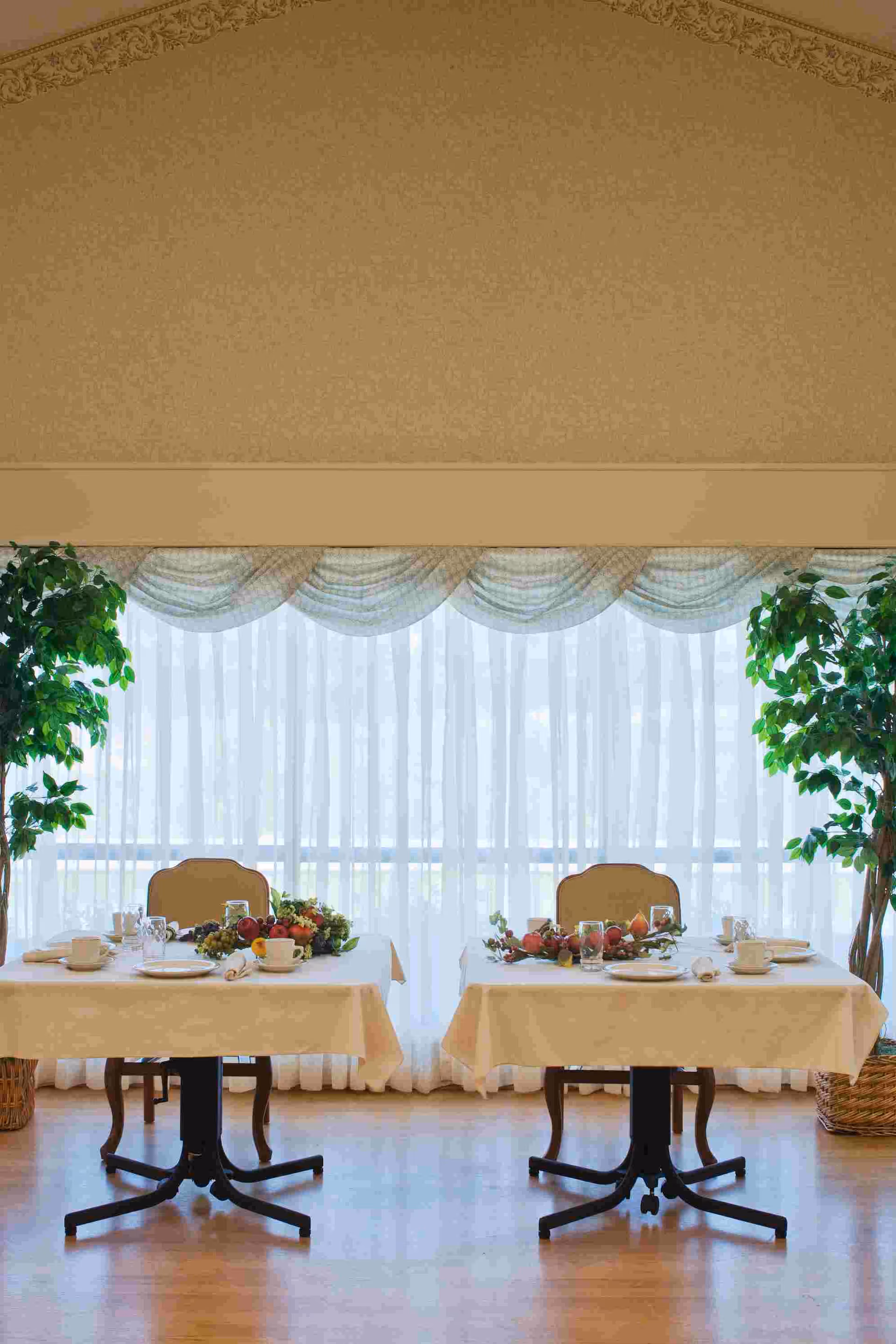 Two banquet-style tables set for a meal in a bright dining room.