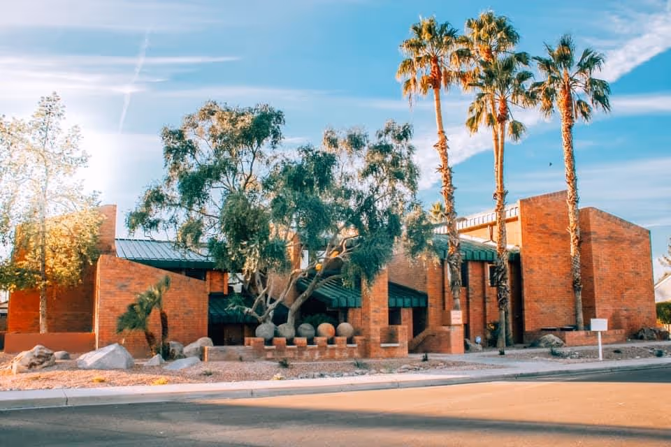 Americare Hospice building exterior with palm trees and blue sky.