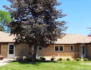 Front view of Oakhill Road senior living building with tree, lawn, and entryway.