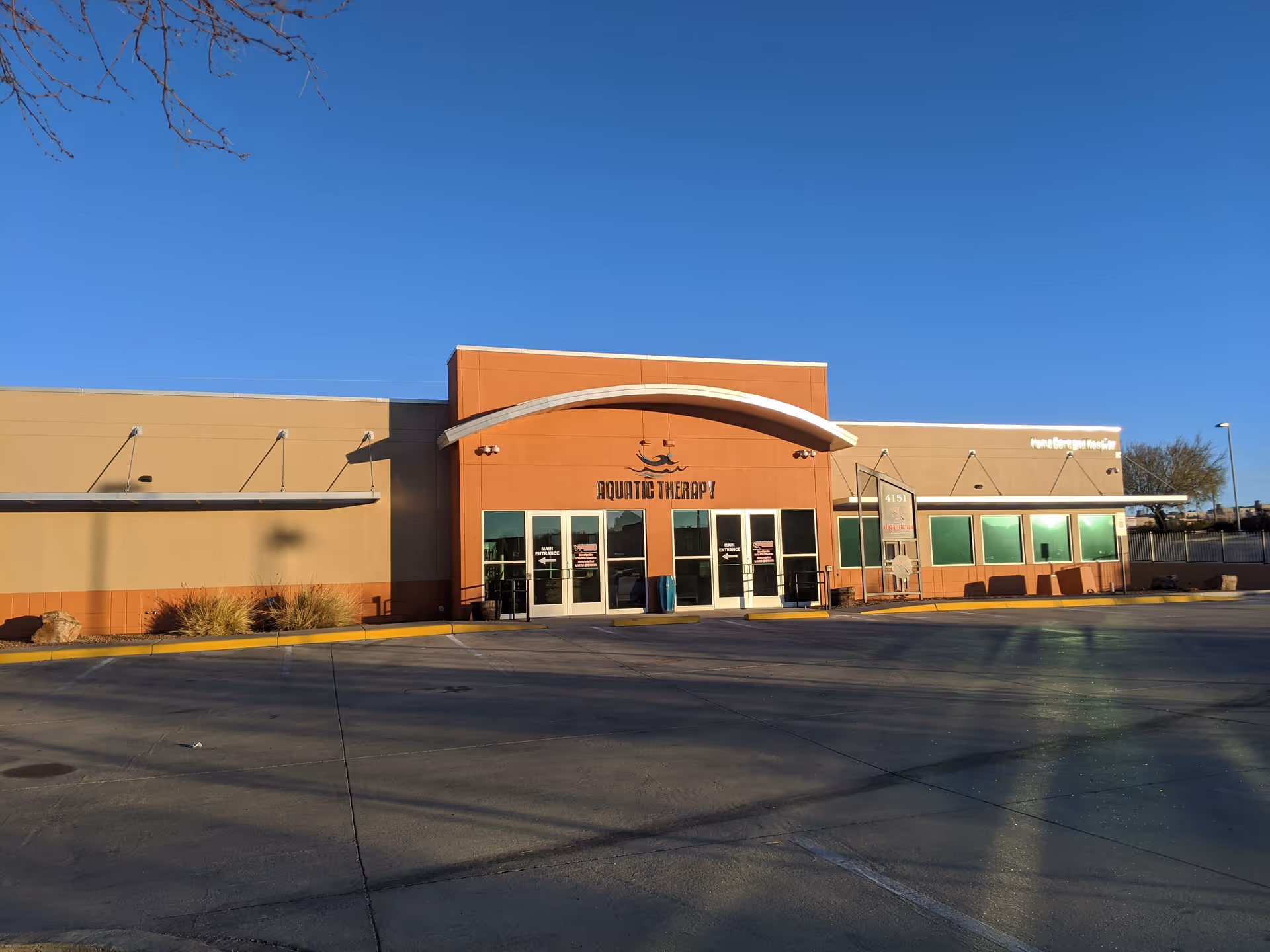 Exterior of a single-story rehabilitation center with orange walls and glass doors