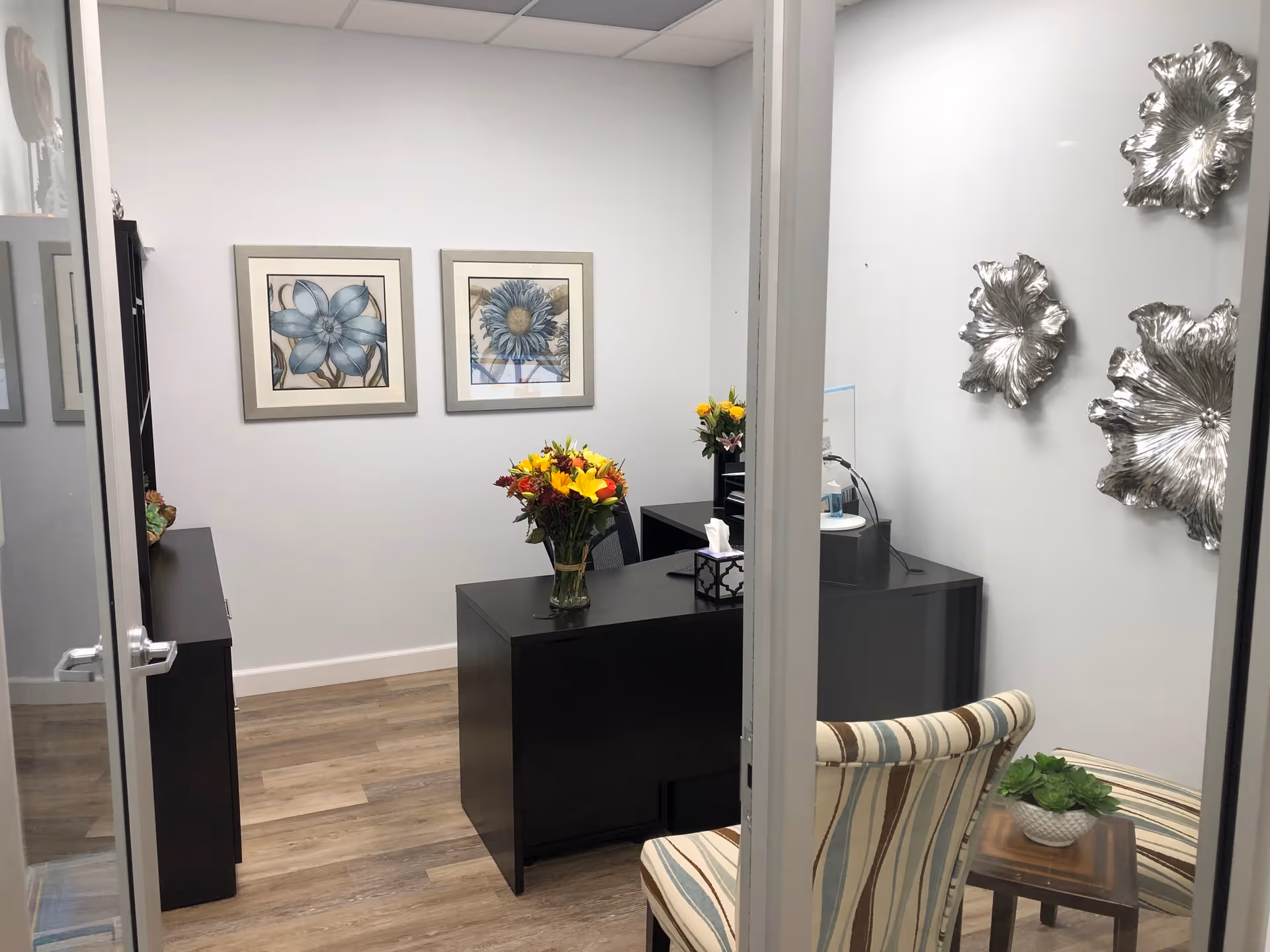 Reception area of a senior care facility with dark desk, flowers, and seating.