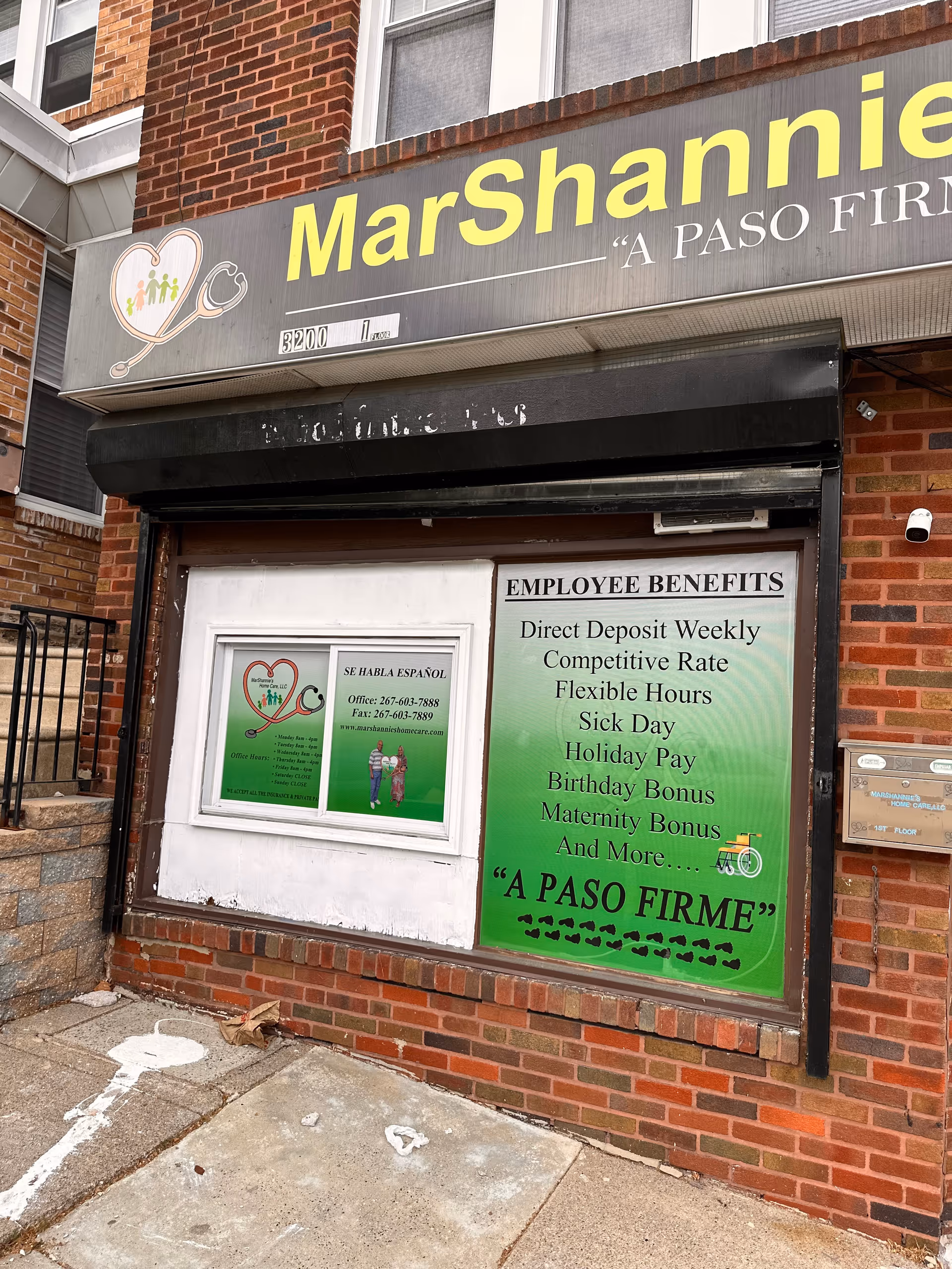Brick storefront with large MarShannies Home Care LLC sign and green employee benefits poster.
