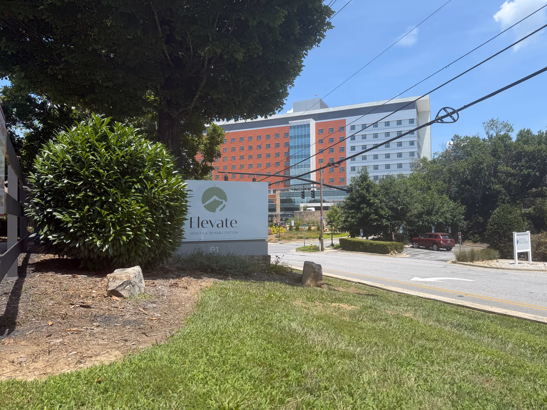 Exterior view of Asheville Nursing & Rehabilitation Center with a sign and street in foreground.