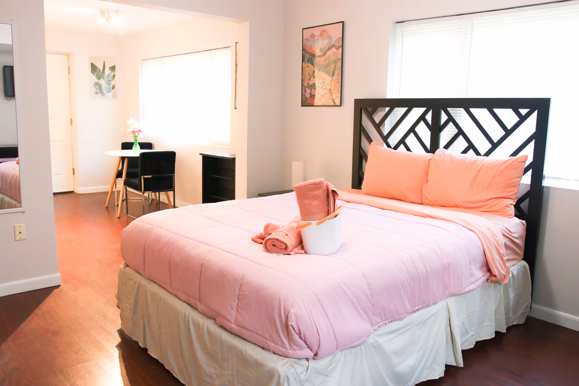 Pink bed with matching comforter and pillows in a bright bedroom with a small desk.