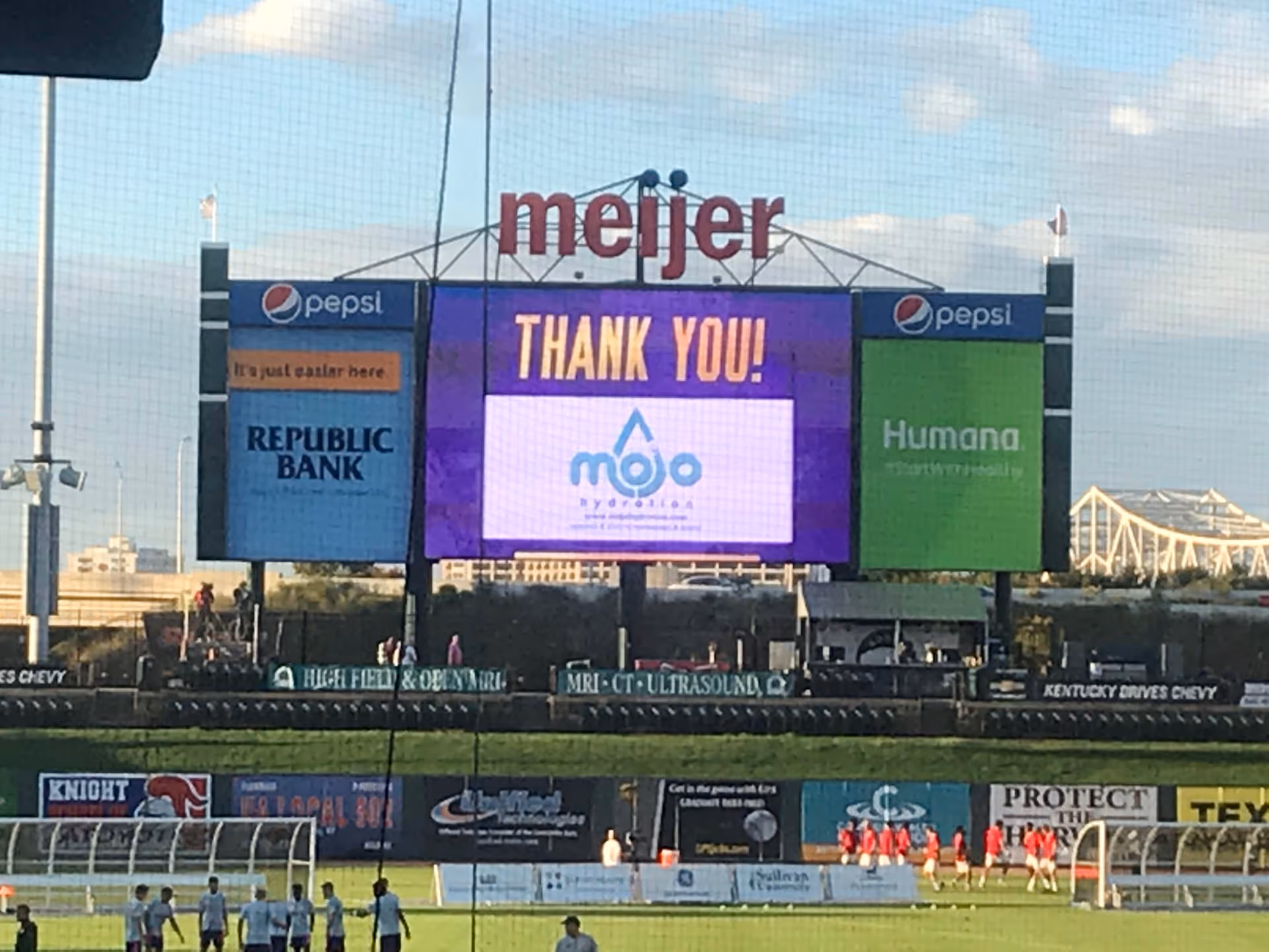 Large outdoor stadium scoreboard showing Mojo Health & Hydration ad with Meijer and sponsors.