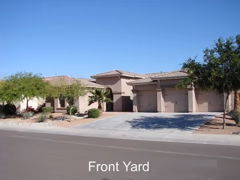Single-story building with a tiled roof, three-car garage and landscaped front yard under a clear blue sky.