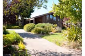 Exterior view of Chaparral House with a walkway, shrubs, and surrounding trees.