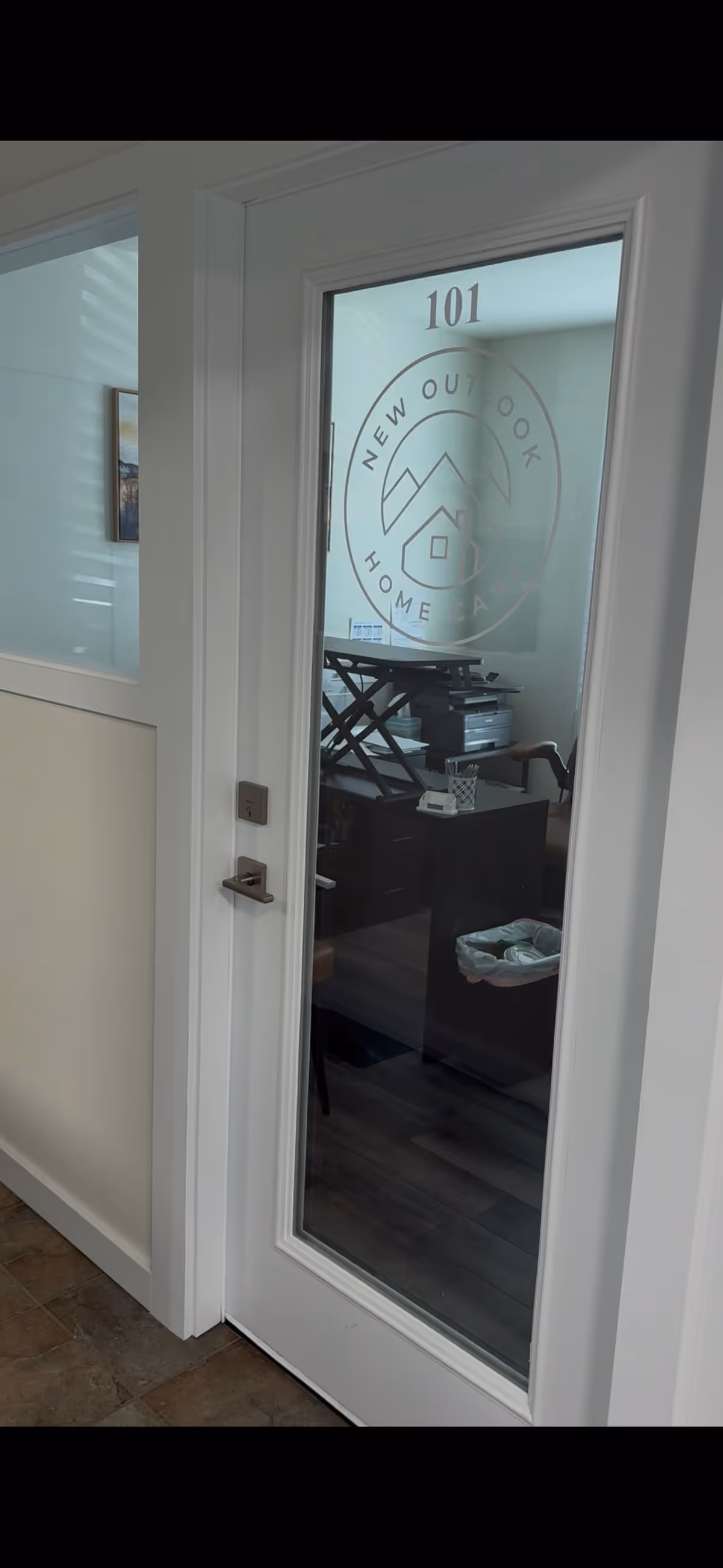 Glass door with 101 and New Outlook Home Care logo leading to an office.