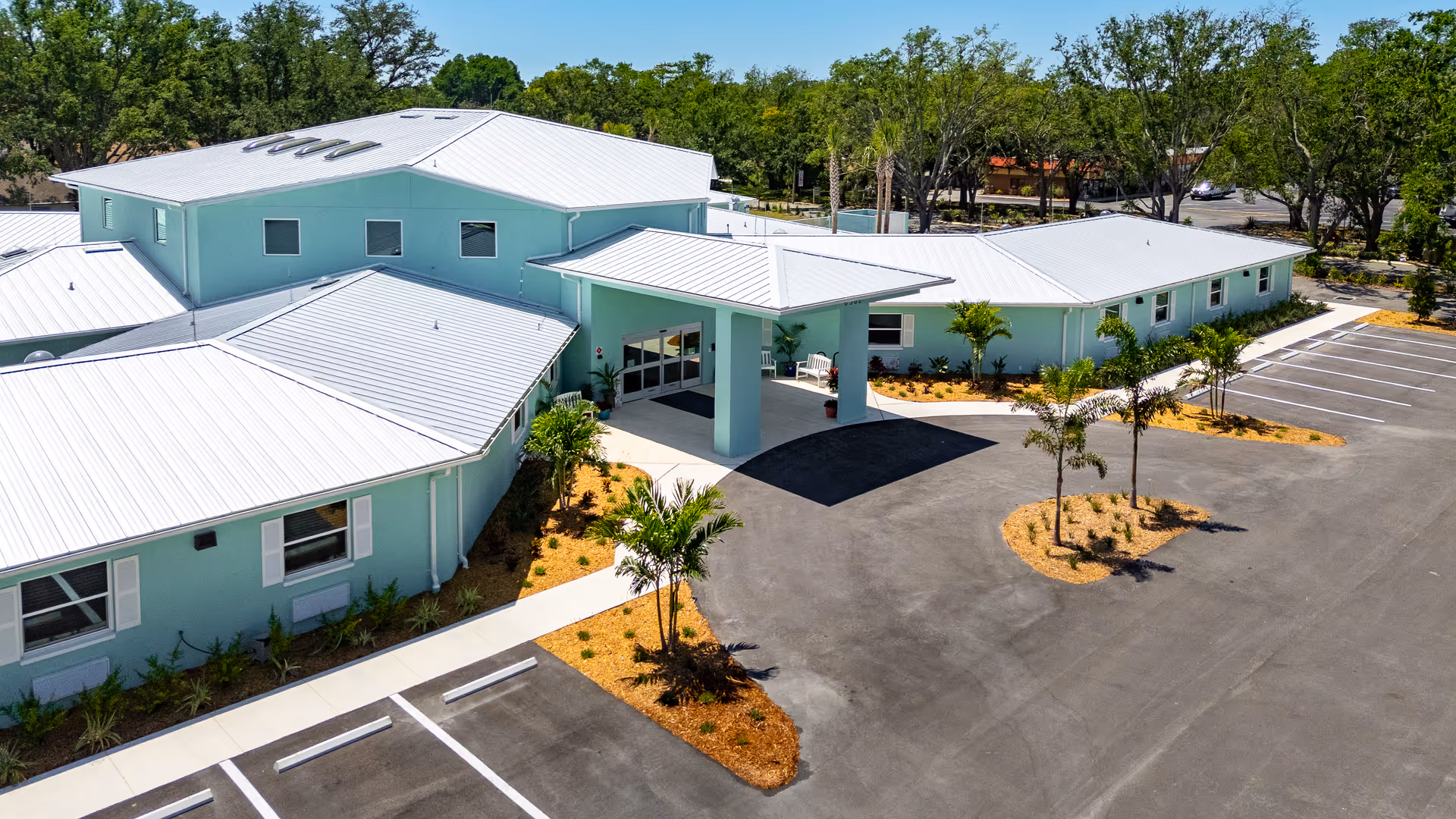 Trinity Memory Care exterior with turquoise walls, covered entrance, and surrounding parking.