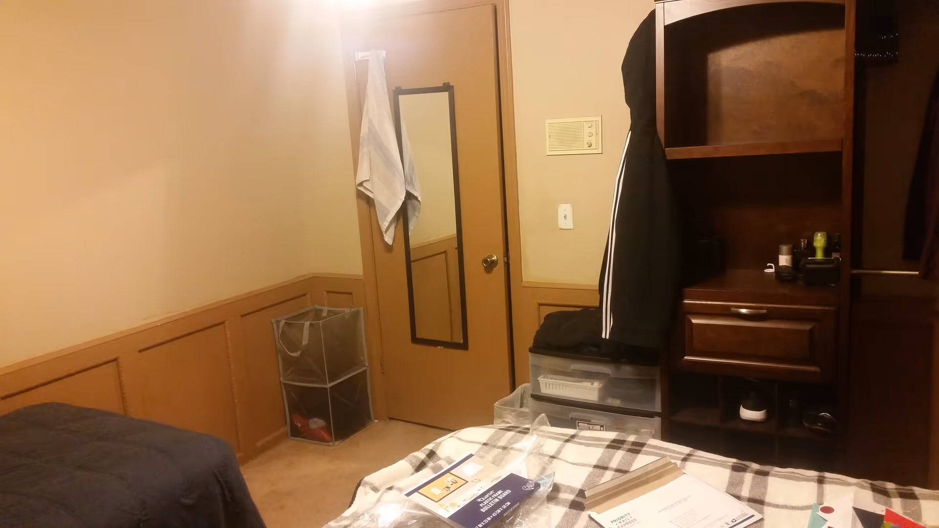 Bedroom with bed, dresser, wardrobe, and clutter near the door.