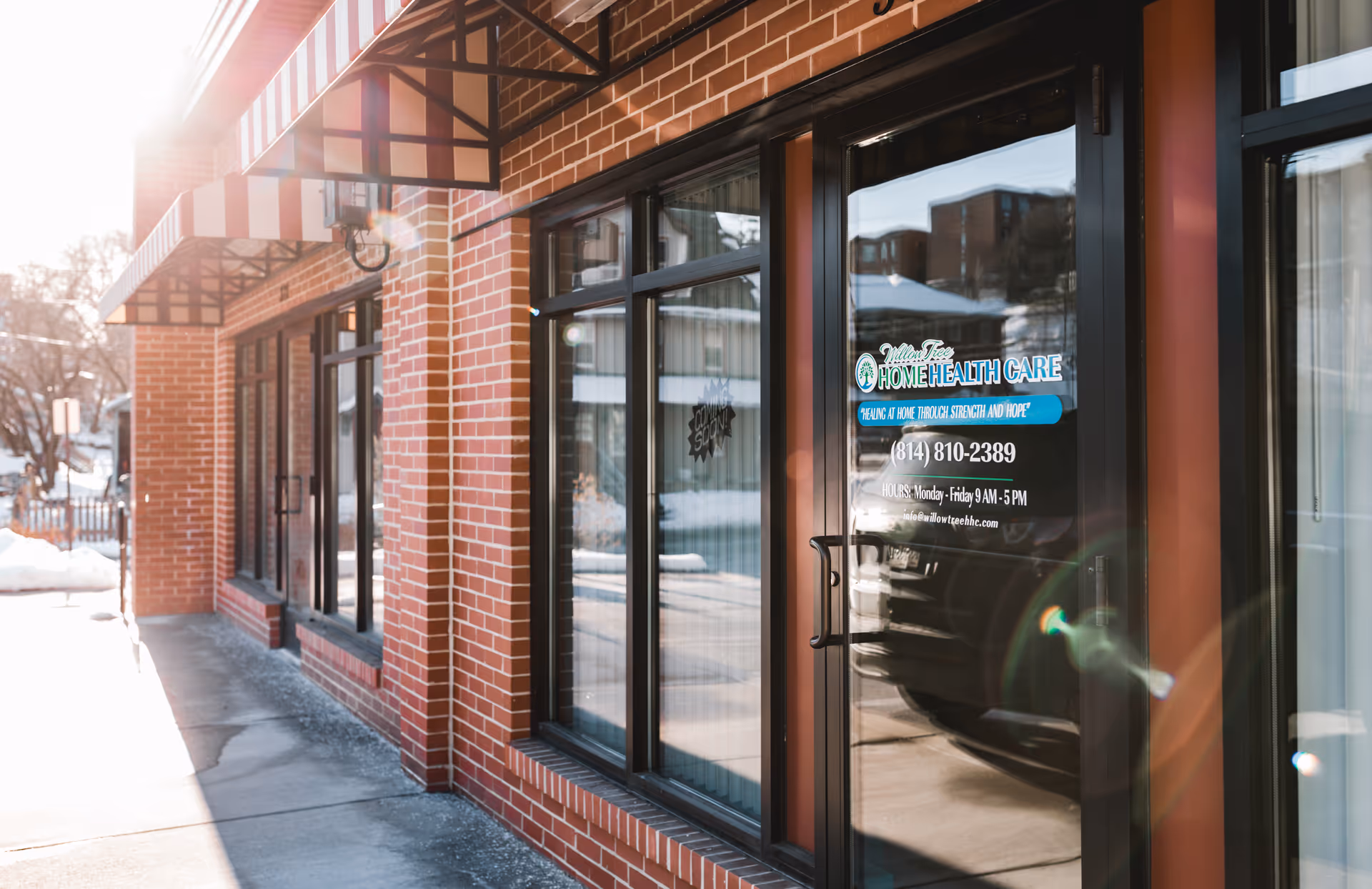 Brick storefront exterior with striped awnings and glass doors labeled Willow Tree Home Health Care.