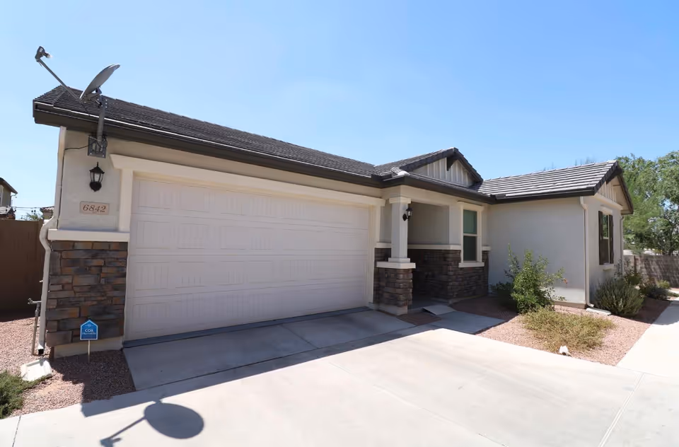 Front view of a single-story building with a two-car garage and desert landscaping.
