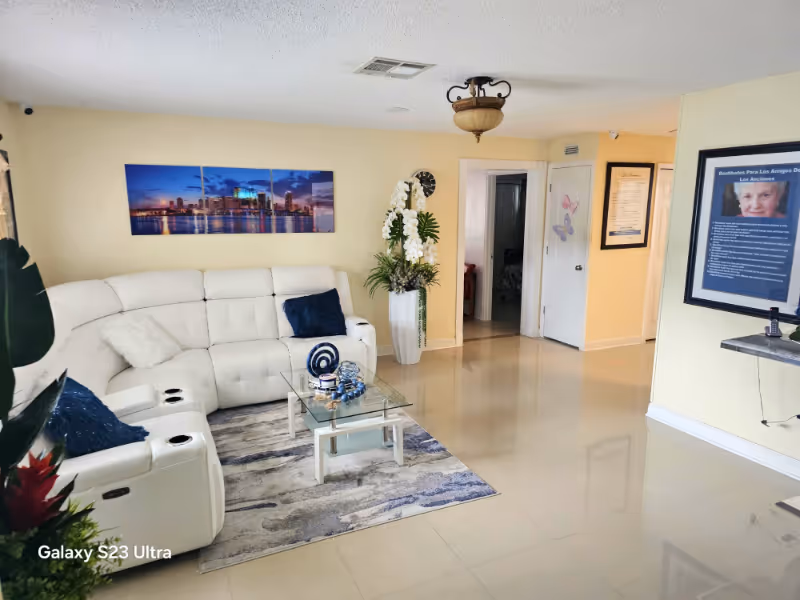 Bright living room with white sectional sofa, glass coffee table, and wall art.