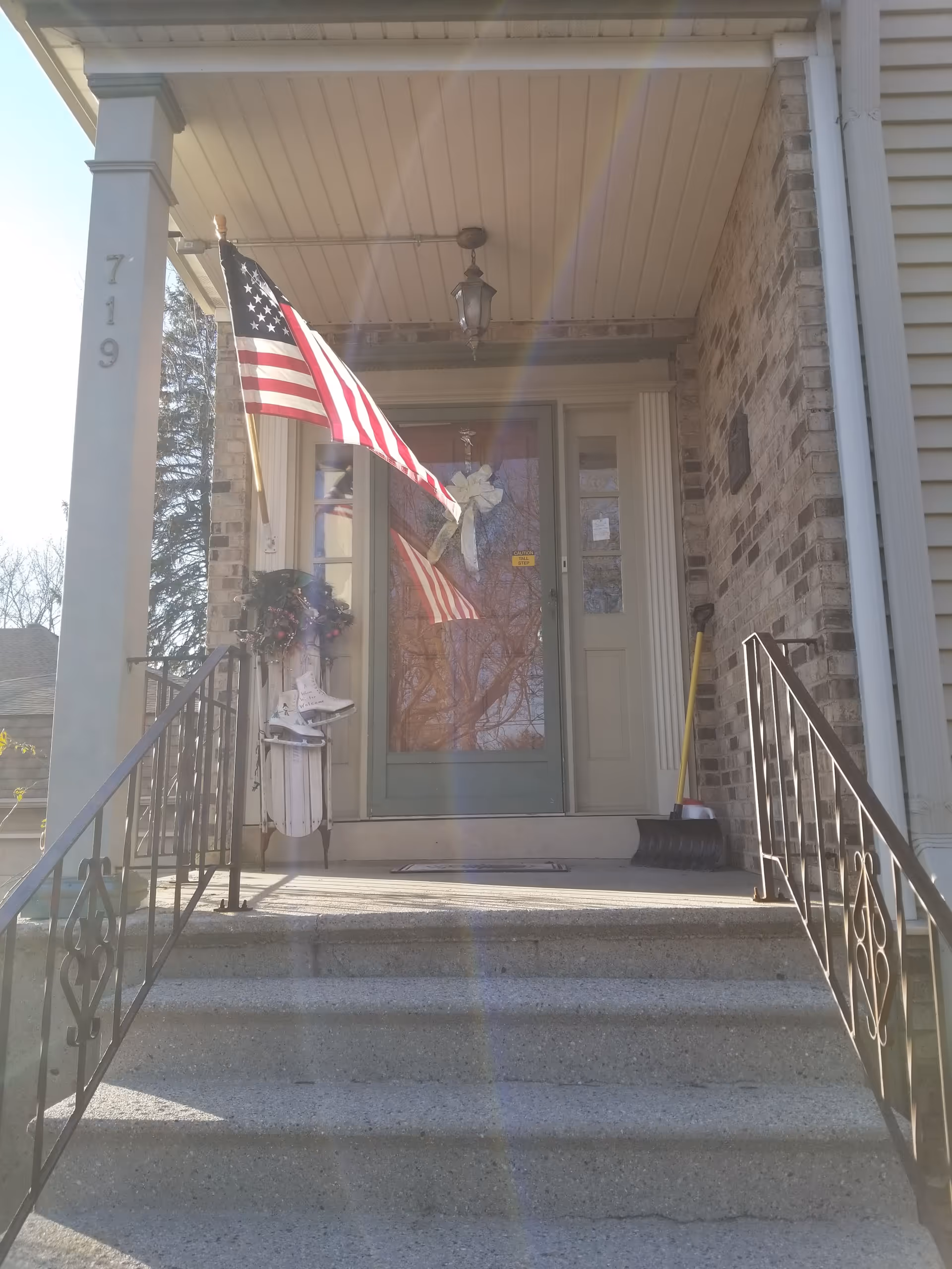 Front entry of Pay-It-Forward House with porch stairs and a waving American flag.