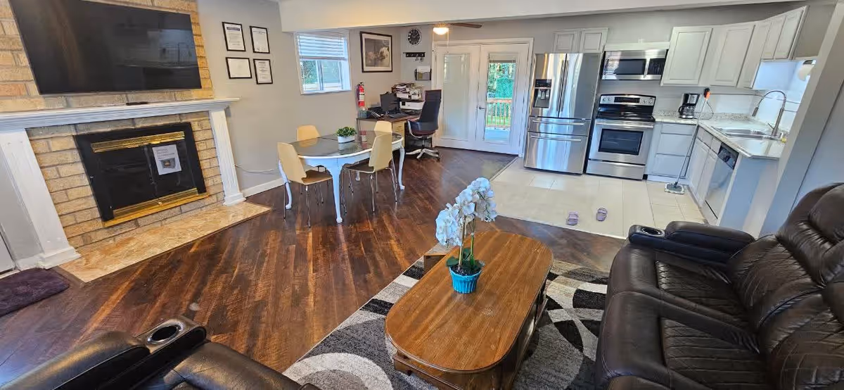 Open-concept living area with fireplace, dining table, and modern kitchen.