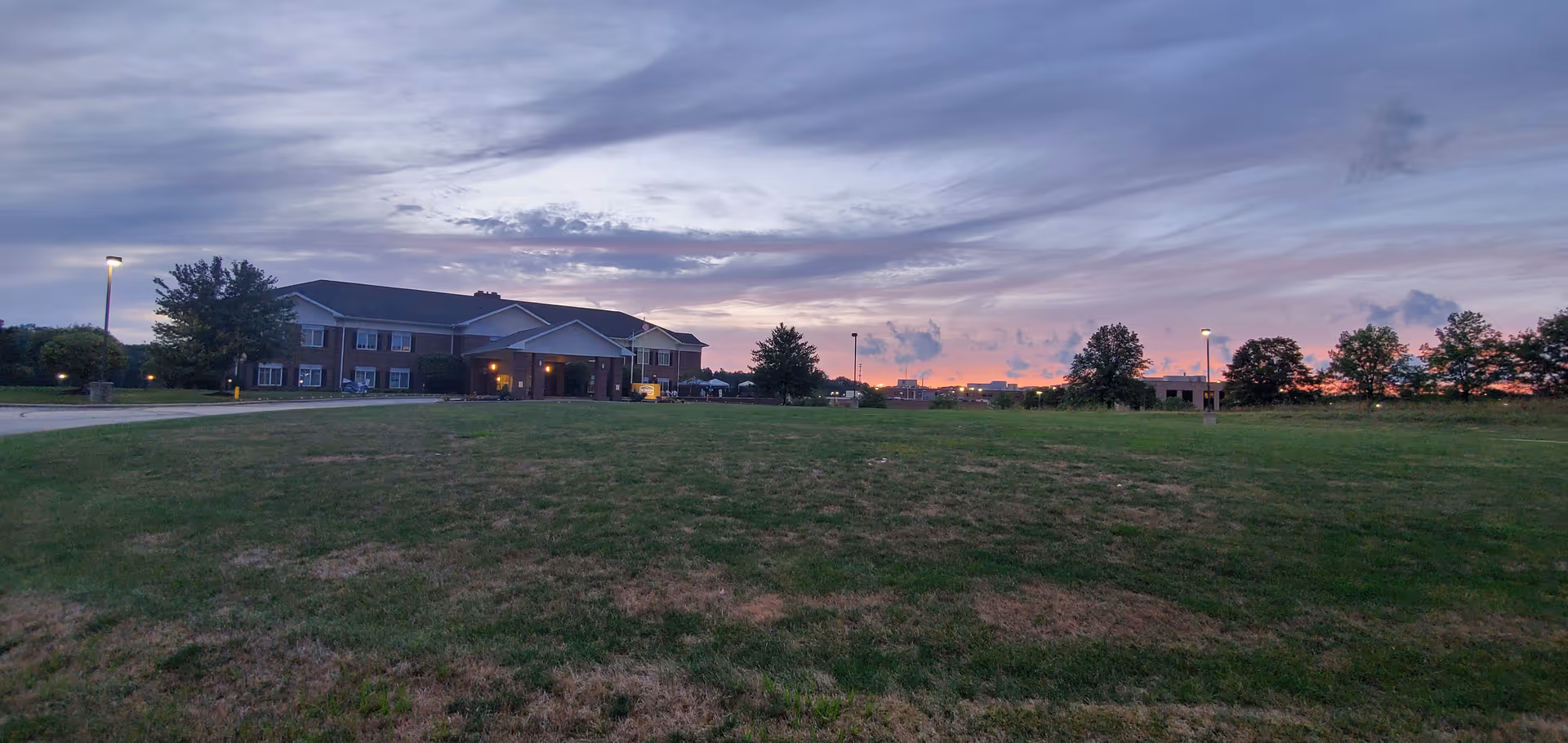 Exterior view of Woodlands Health and Rehab Center at dusk, with a large lawn and entrance.