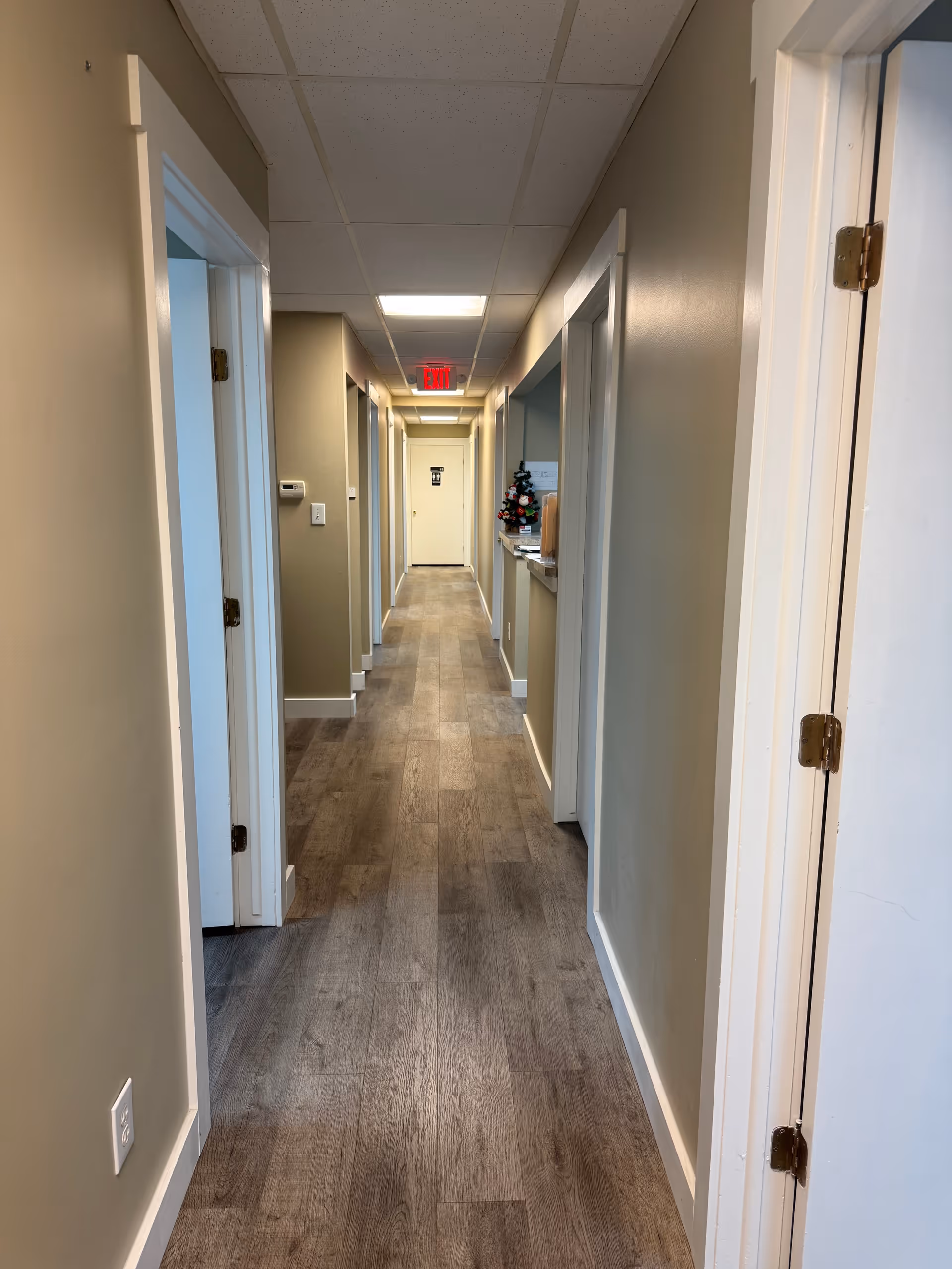 Narrow hallway inside a senior care facility with doors on both sides and a reception area.