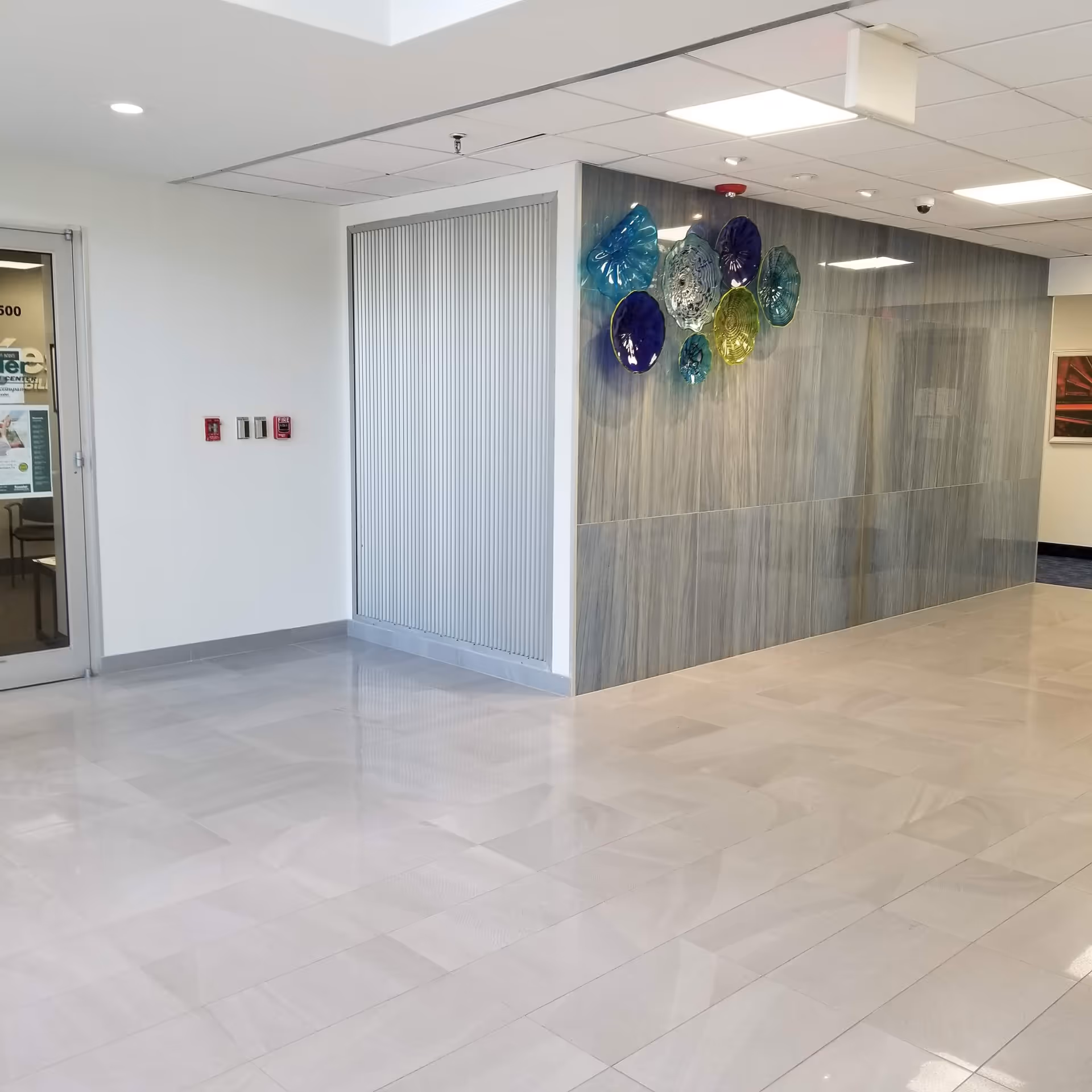Interior lobby hallway of Home Helpers of Freehold with tiled floor and glass wall art.