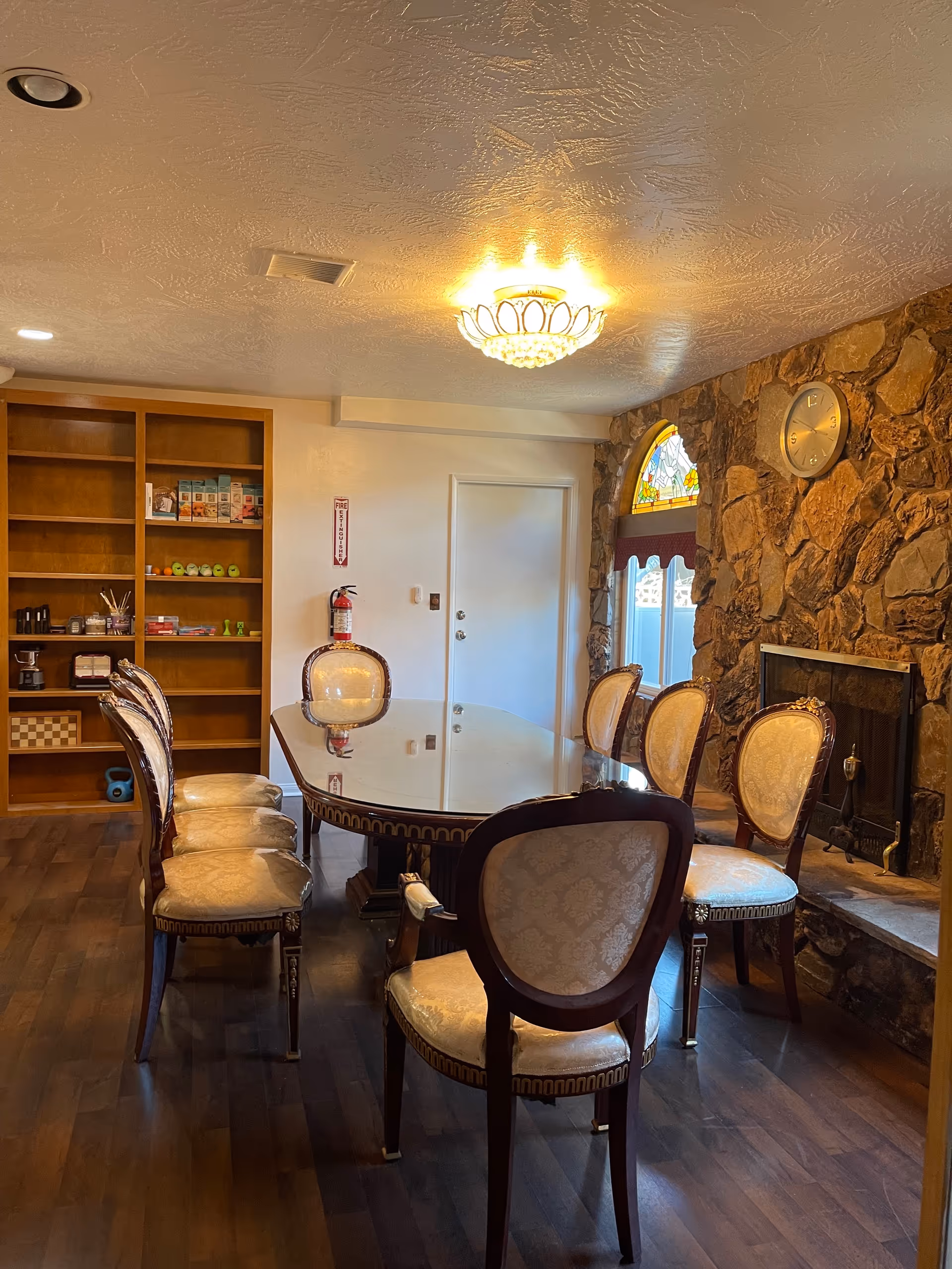 Elegant dining room with a round glass table, upholstered chairs, and a stone fireplace.