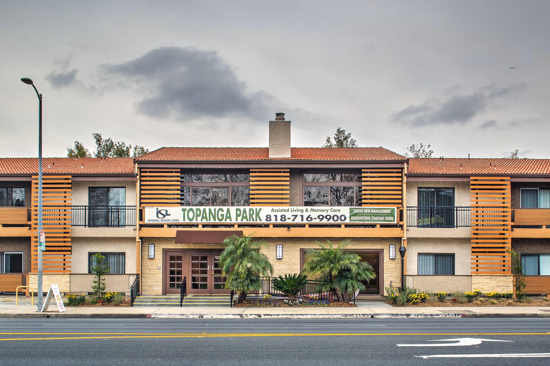 Front view of Canyon Trails at Topanga Senior Living building with sign and palm landscaping.