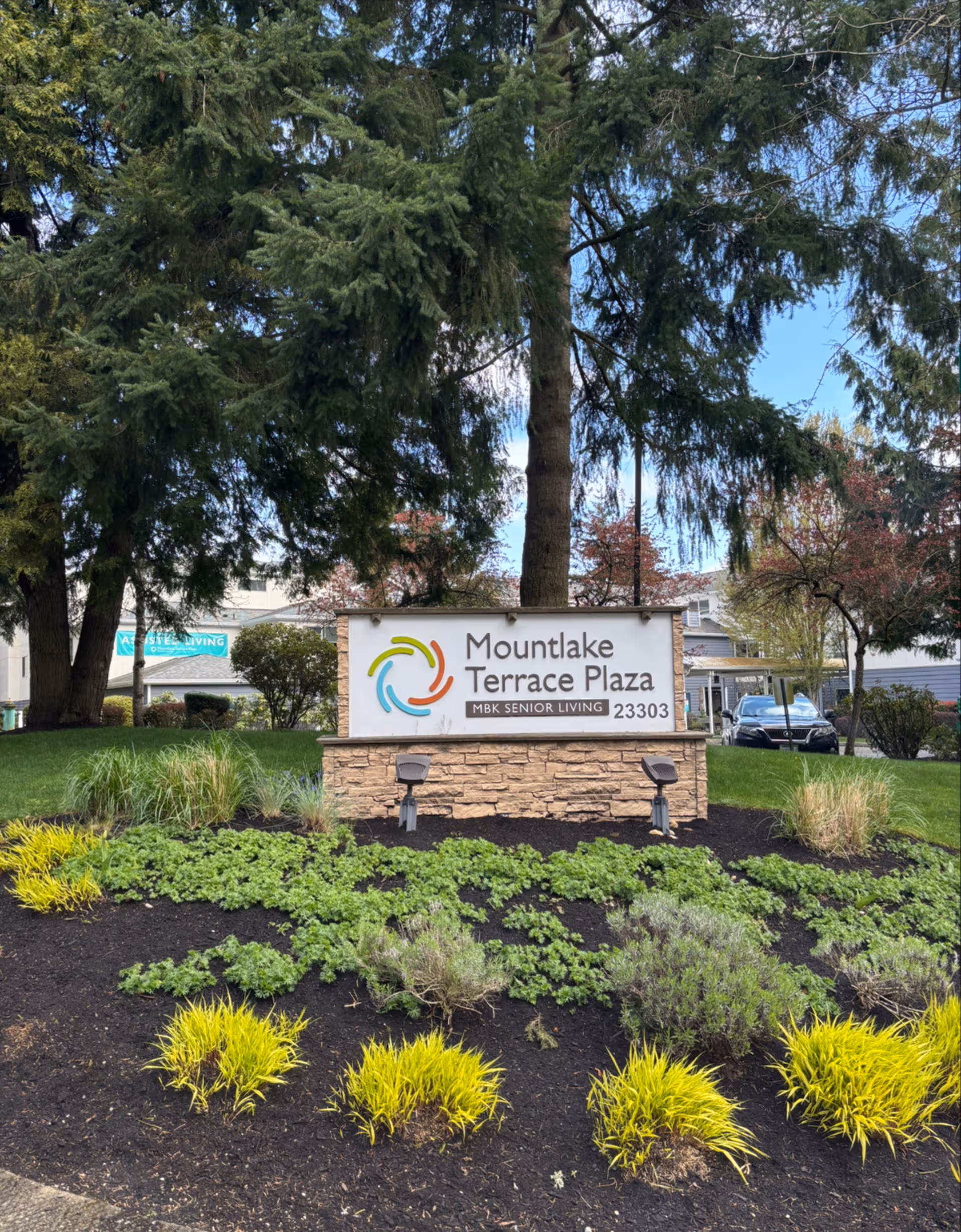 Front sign for Mountlake Terrace Plaza with landscaping and trees.