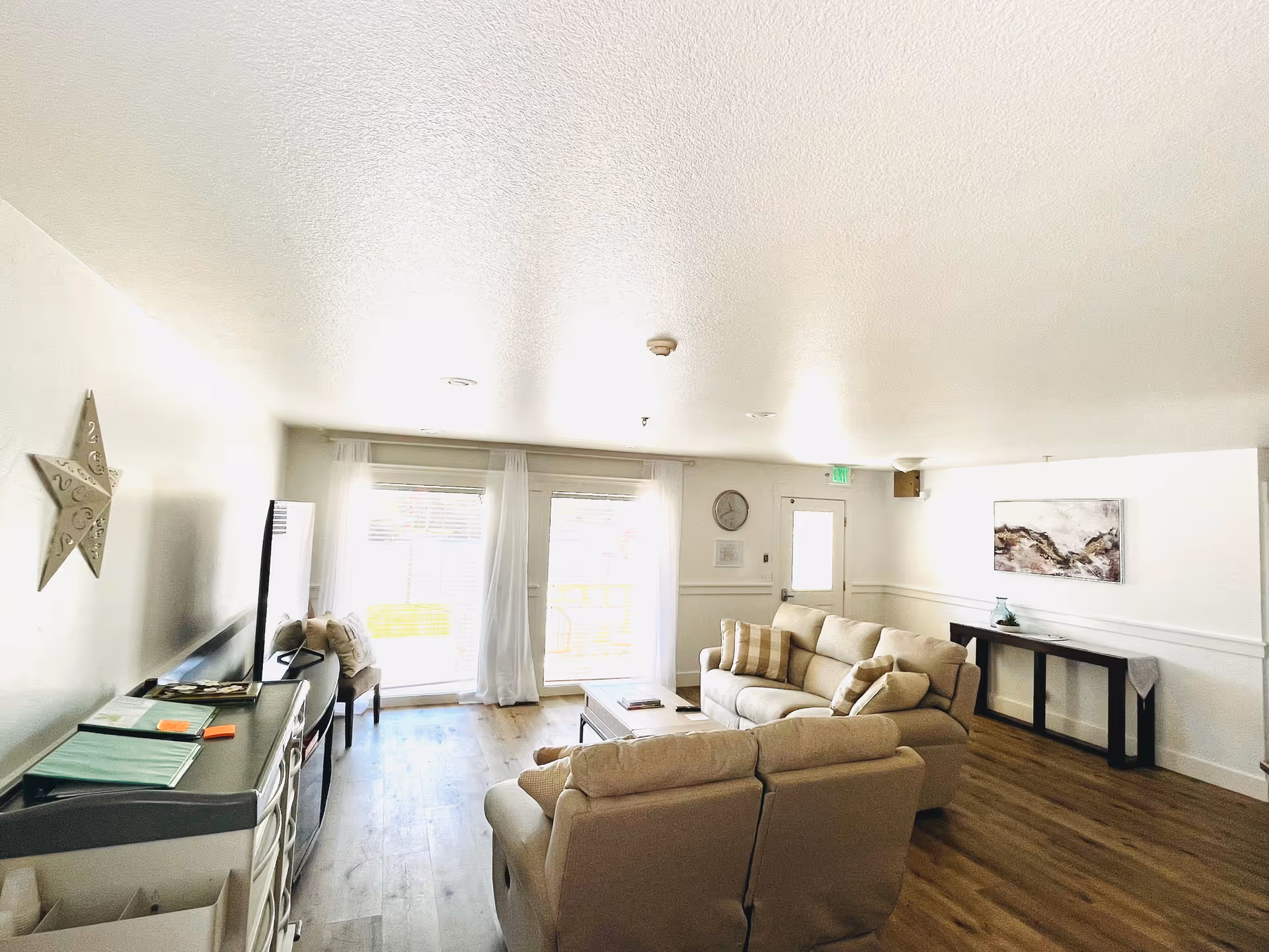 Bright living room with beige sofas, a TV, and sliding glass doors.