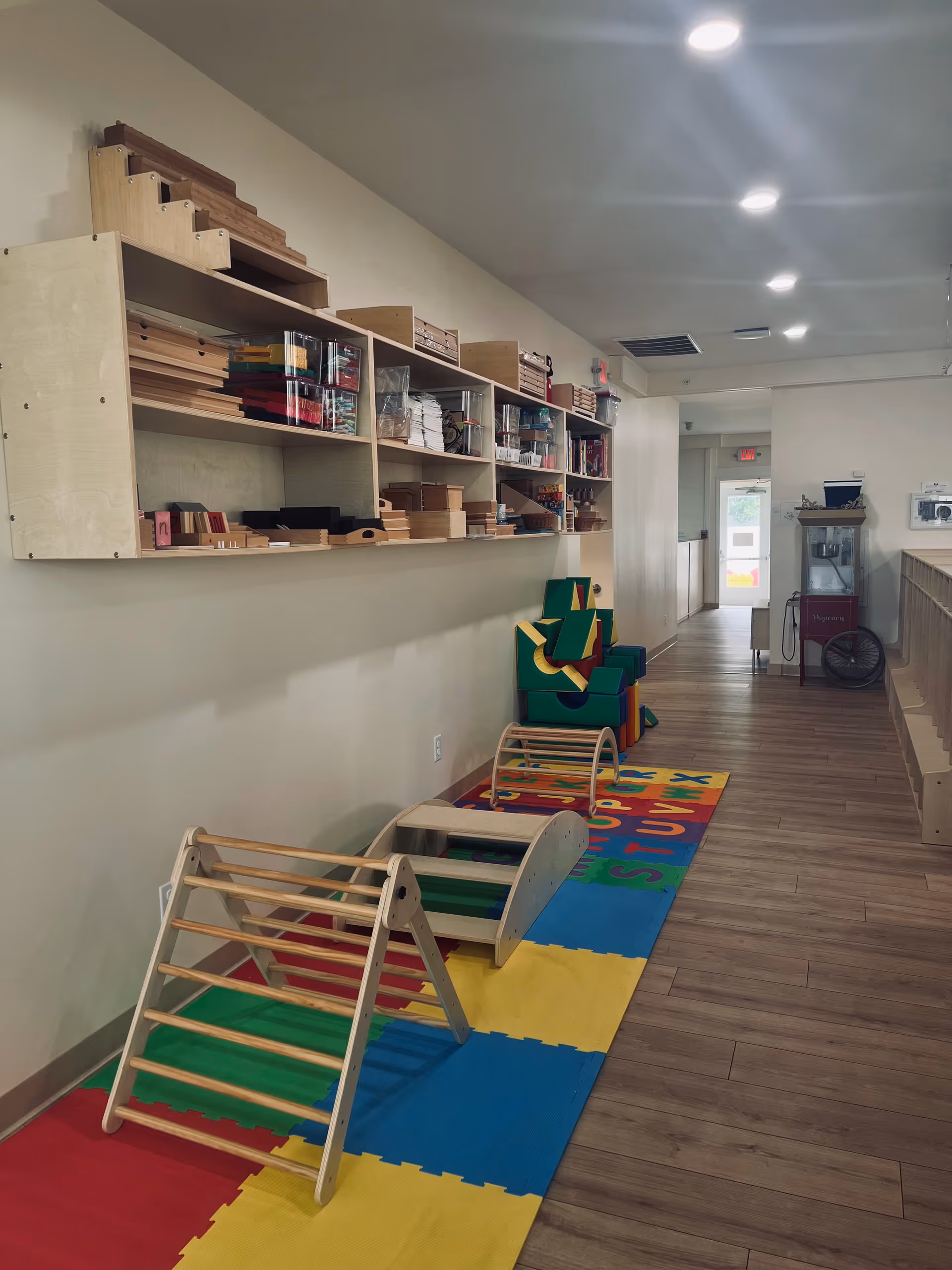 Long hallway with shelves of craft supplies and colorful children's play mats