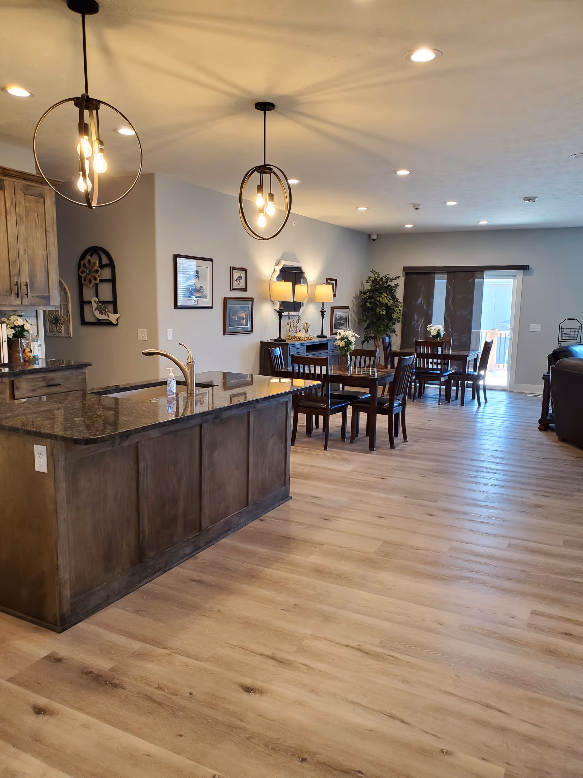 Open senior living area with a dark wood kitchen island and dining tables.