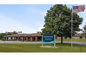 Front exterior of a single-story assisted living facility with flagpole and sign.