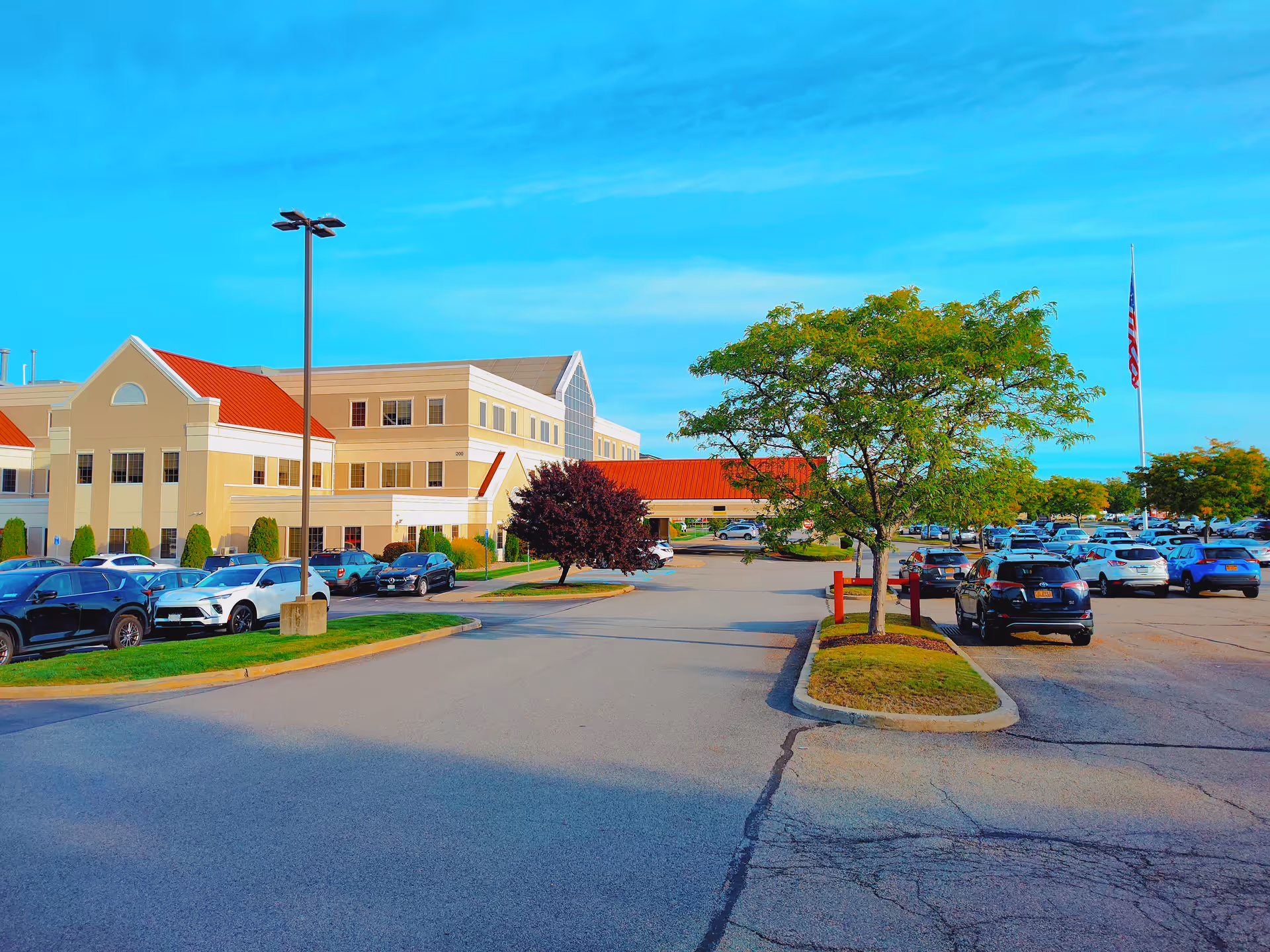 Exterior view of a senior living facility with parking and trees under a blue sky.