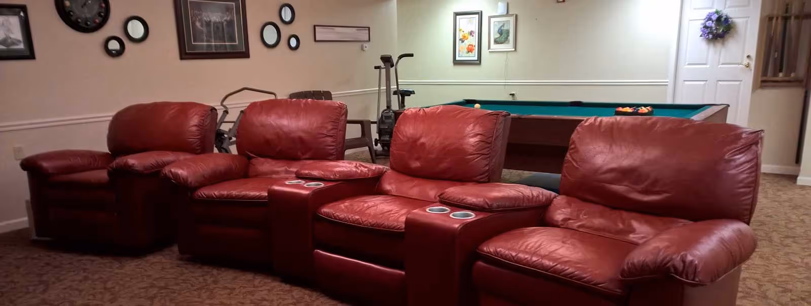 Red leather recliners form a lounge with a pool table in the background.