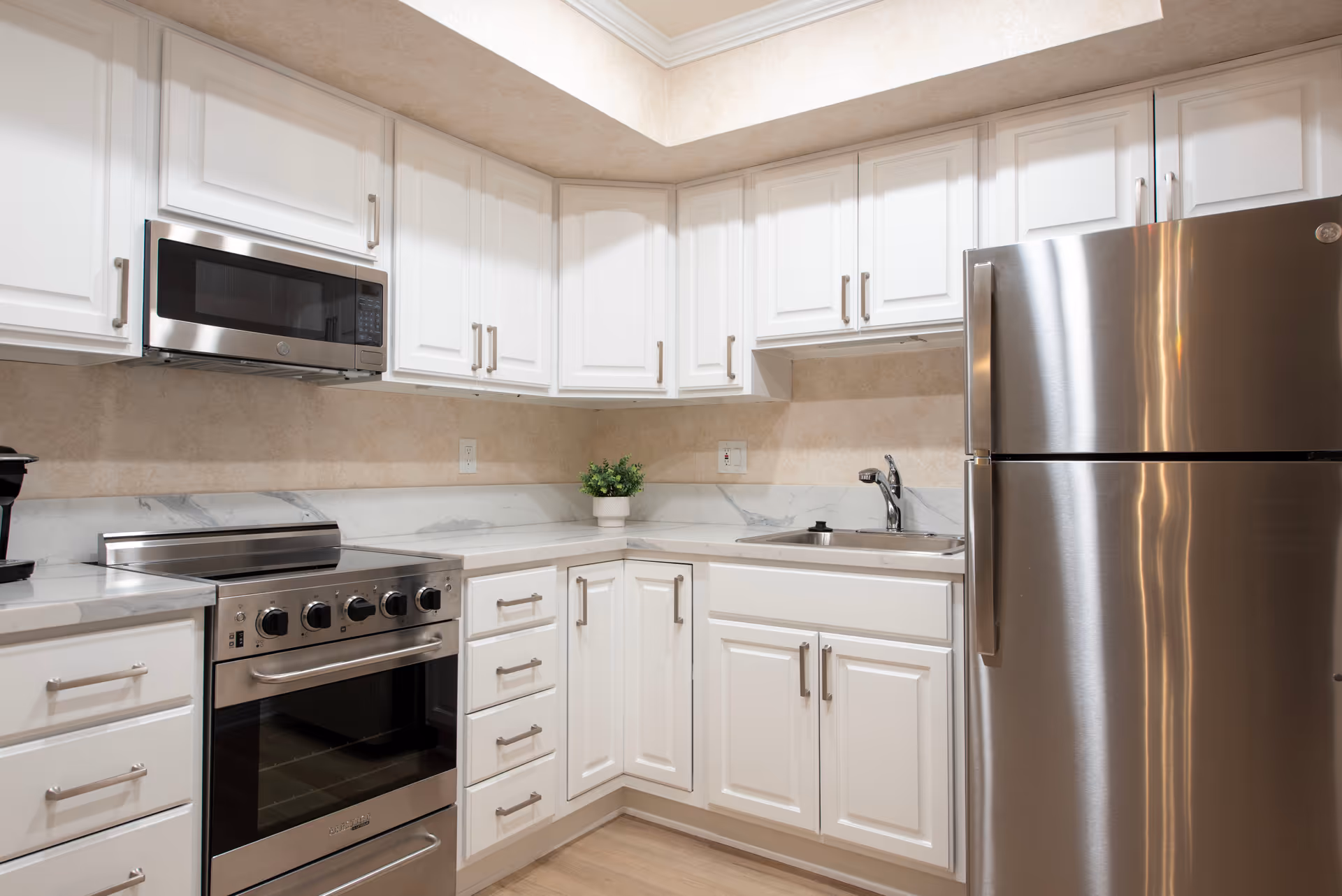 White kitchen with cabinets, stainless appliances, and marble-like countertops.