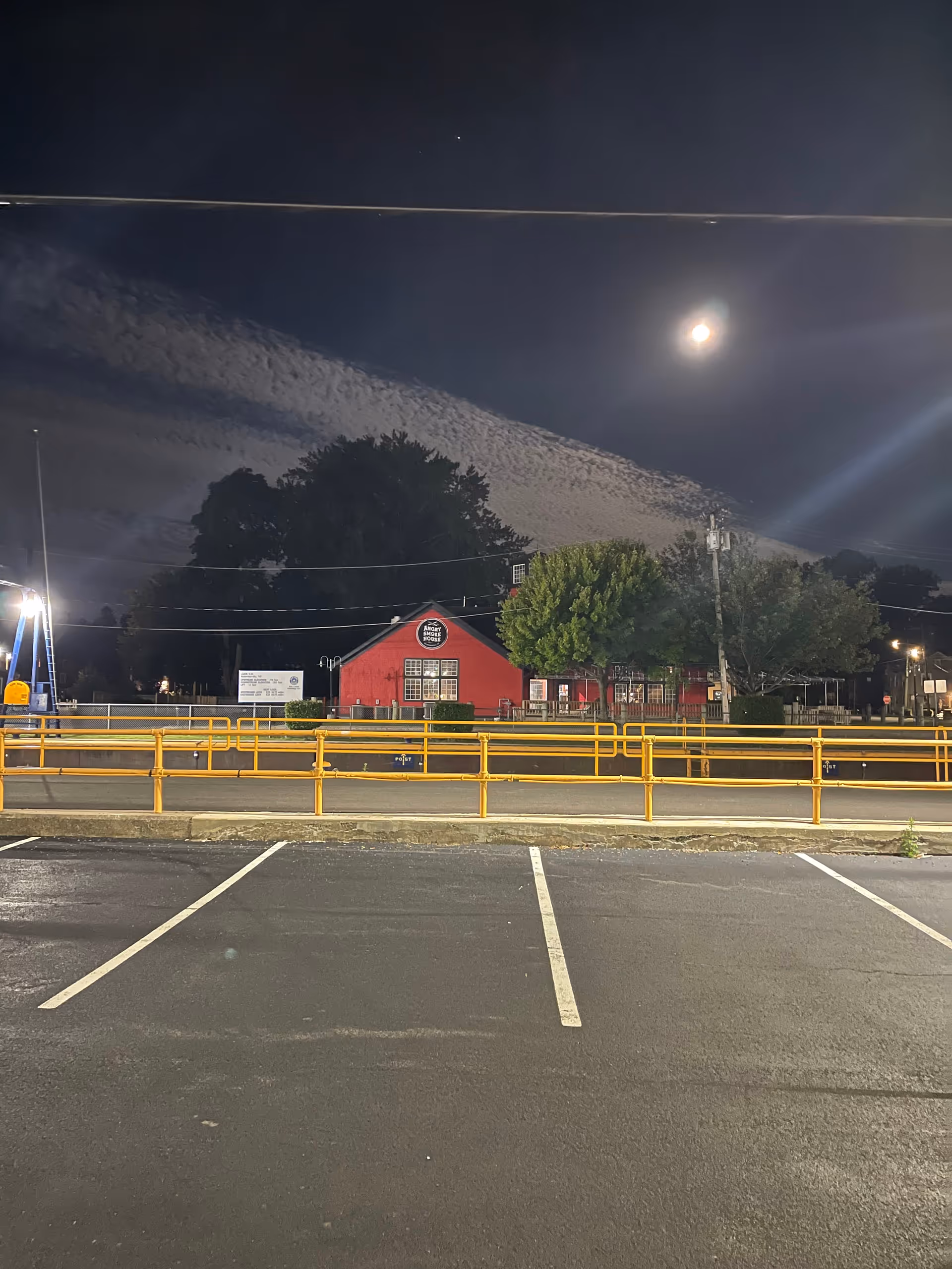 Night exterior of a red building with yellow railings and parking lot at Red Mill Manor.