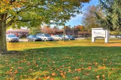Exterior view of Valley View Healthcare Center with parked cars and a leafy lawn.
