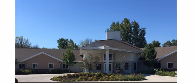 Exterior view of Milan Estates senior living facility with a landscaped entrance and driveway.