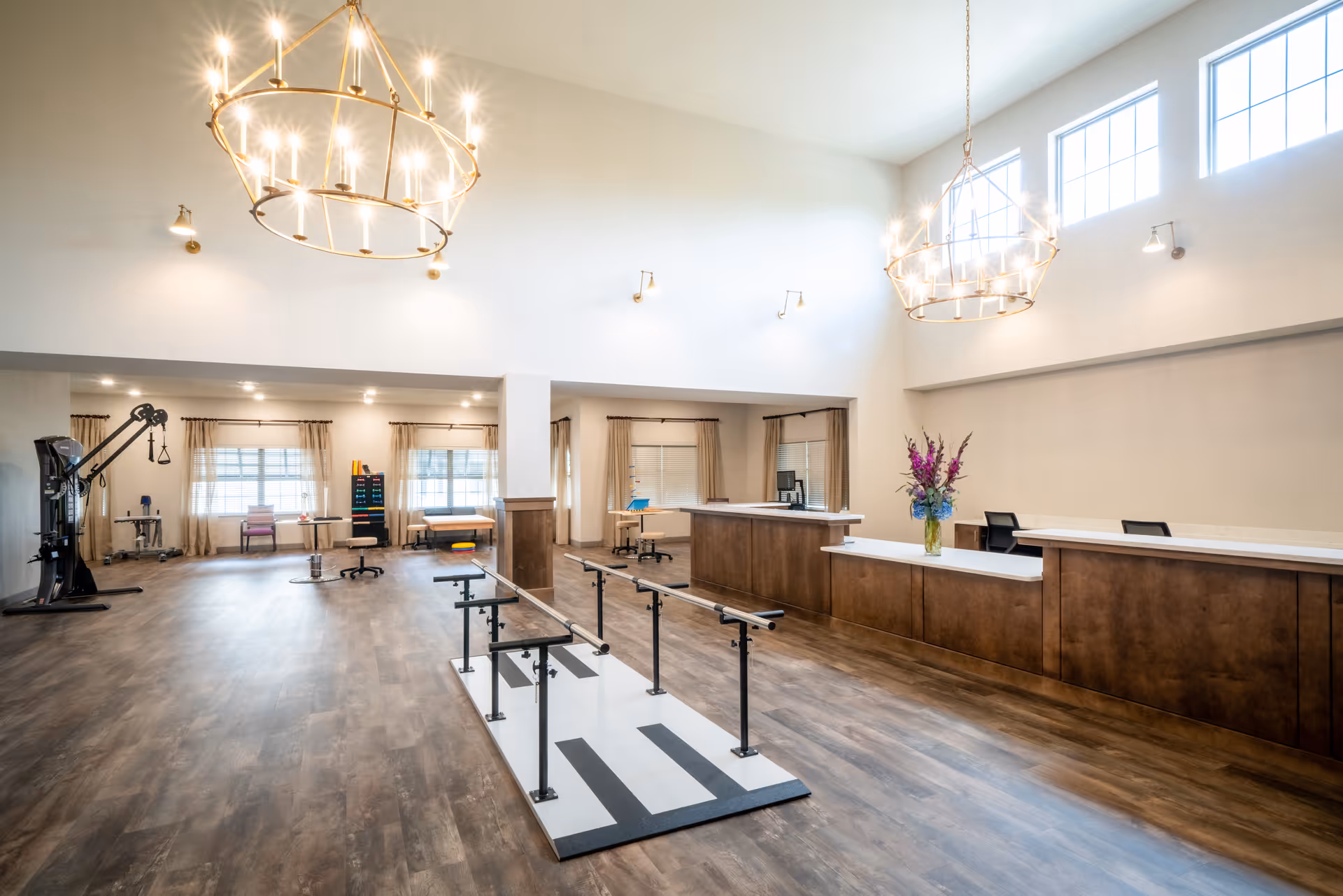 Bright open fitness area with gym equipment and a reception desk in a senior facility.