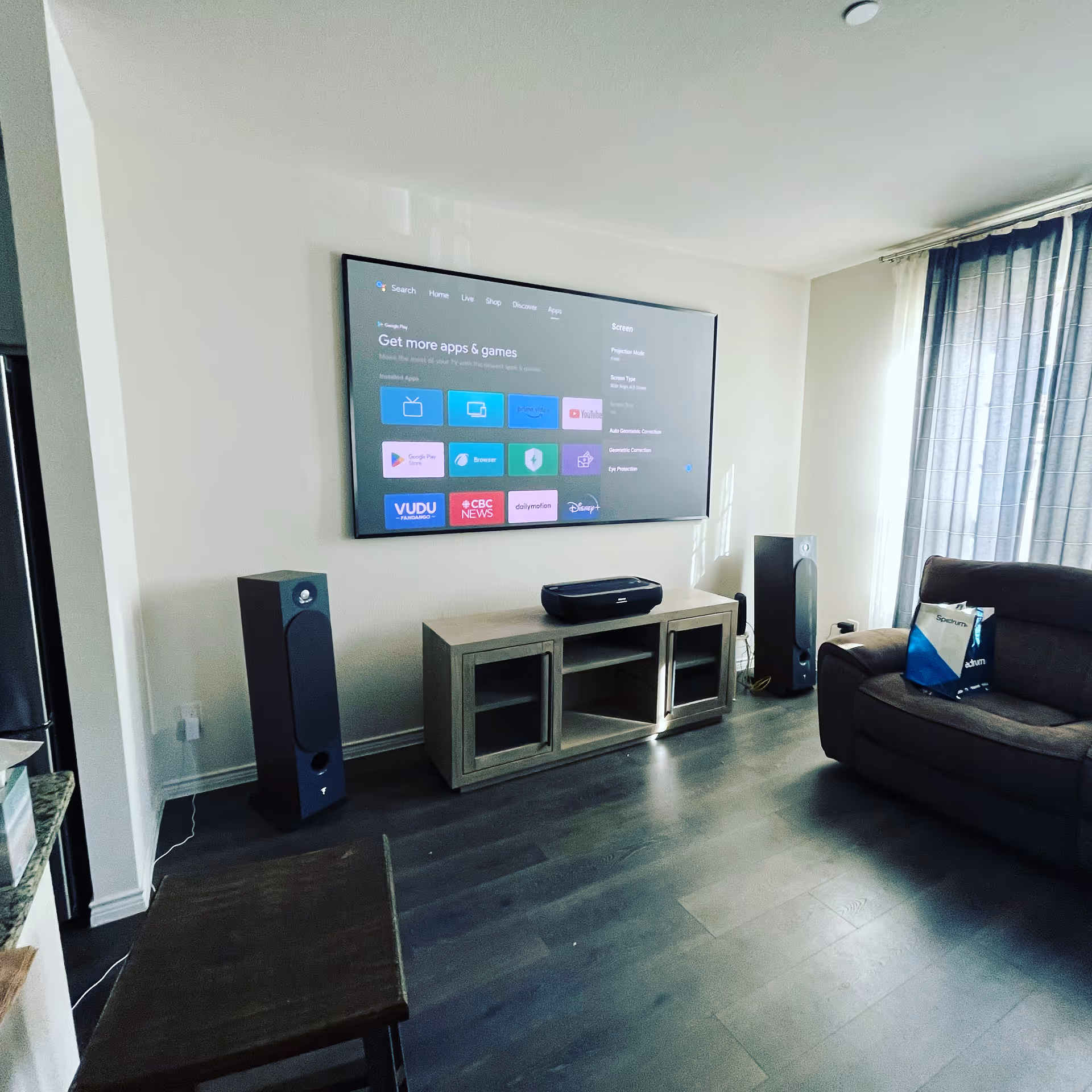 Living room featuring a wall-mounted TV, speakers, media console, and sofa.