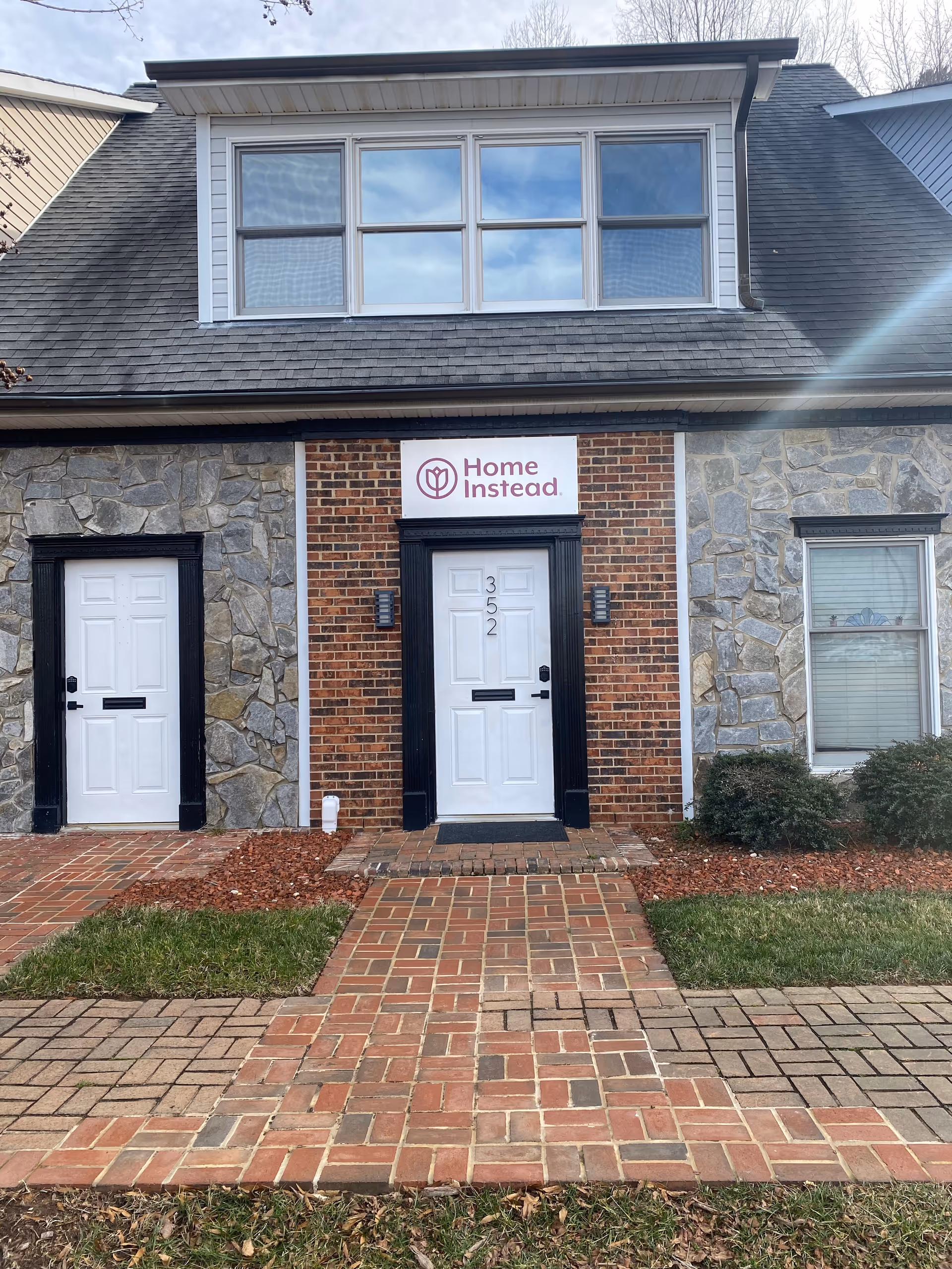 Front of a brick-and-stone building with two doors and a Home Instead sign