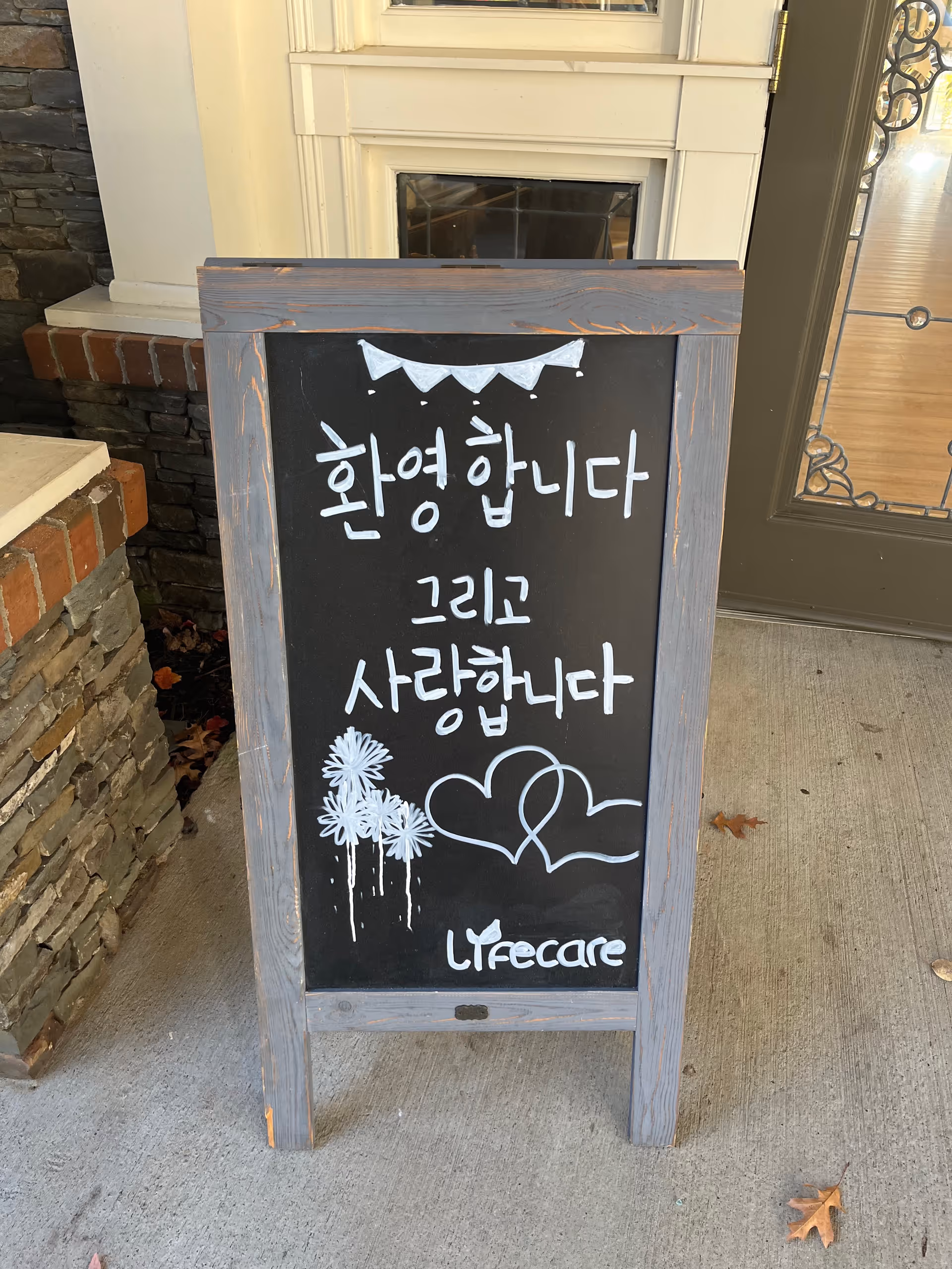 Chalkboard welcome sign with Korean message outside the Lifecare entrance.