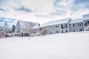 Snow blankets the front of a modern senior living facility, The Golden Crest.